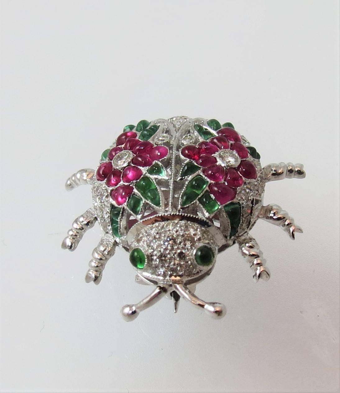 Fabulous 18K white gold beetle pin, set with 20 cabochon rubys, 28 cabochon emeralds, and 47 round diamonds about 1.20 cts, with adorable articulating legs.

One inch wide by one inch long