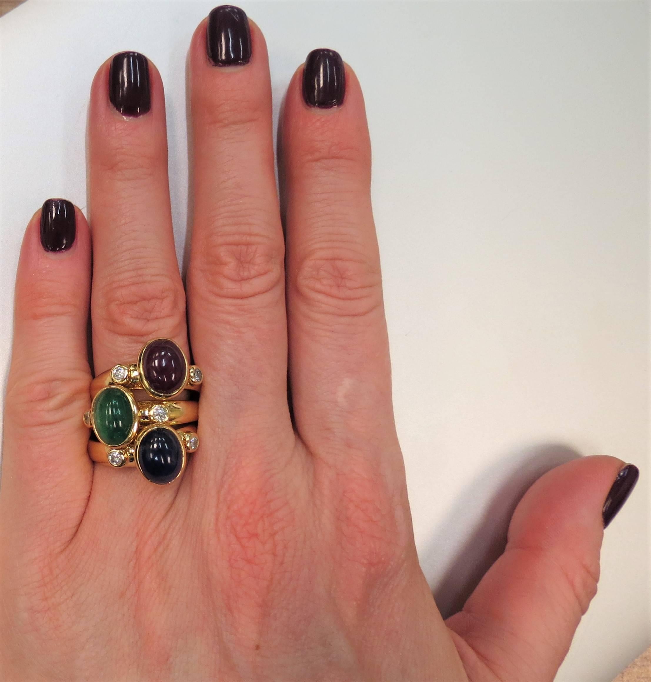 Suite von drei Ringen: 18K Gelbgold mit Cabochon Saphir, Cabochon Smaragd, Cabochon Rubin Diamantringe. Jeder Ring hat zwei runde Diamanten im Vollschliff mit einem Gewicht von ca. 0,20 ct., die in einer Lünette gefasst sind. Der Schaft misst oben