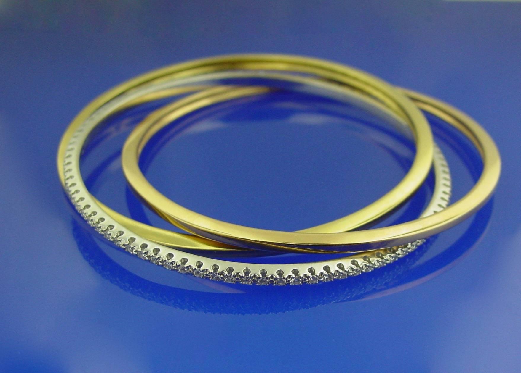 An 18 karat  tri -colored gold and diamond bangle. This versatile and modern piece interlocks a 3mm rose gold bangle, a 3mm yellow gold bangle and a 3mm round brilliant diamond white gold bangle. Approximate carat weight: 1.75 carats. Very nicely
