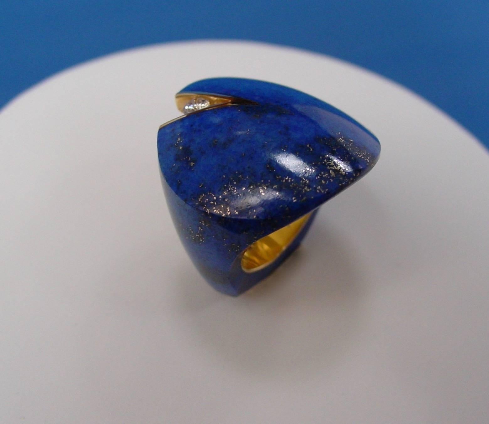 This unique and very lovely ring is composed of a single carved piece of lapis lazuli, lined in 18 karat yellow gold and artfully accented by a round brilliant diamond. Engraved 750 BDW
Ring is sized 7 1/2 and is not sizable
Approximate diamond