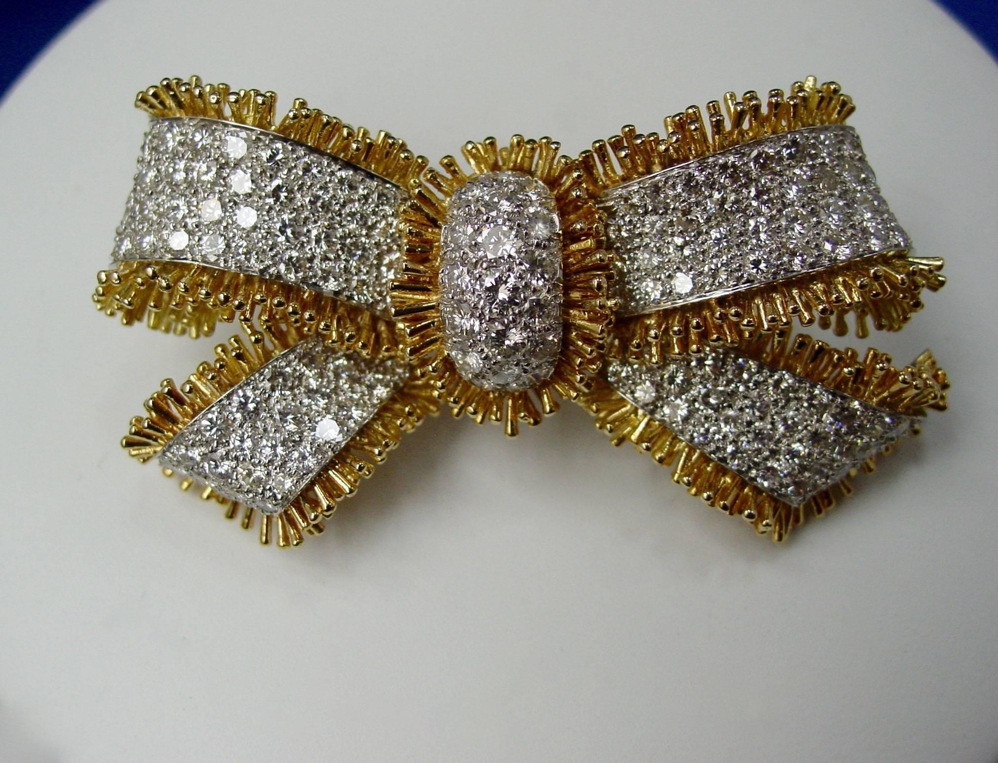 A gorgeous diamond bow brooch by the incomparable David Webb. Beautifully crafted with approximately eight carats of round brilliant diamonds mounted in platinum and a textured fringe of 18 karat yellow gold.