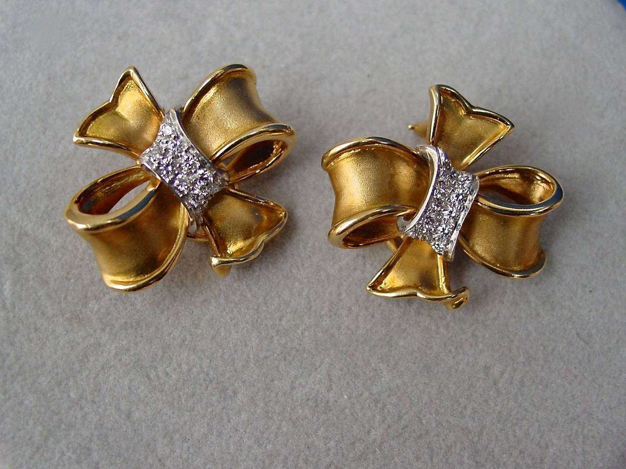 A pair of finely made satin finished 18 karat yellow gold, platinum and diamond bow ear clips. Set with twenty round brilliant diamonds weighing approximately .60 carats. Stamped SB 18K Plat.