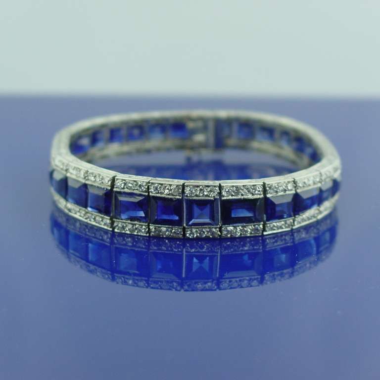 An art deco sapphire and diamond line bracelet mounted in platinum. The bracelet is set with approximately 18.75 carats of emerald and square shaped sapphires set between two rows of round shaped diamonds weighing approximately 3.40 carats. The