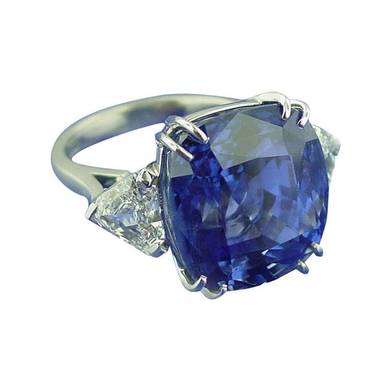 A platinum, sapphire and diamond ring centering a 27.49 carat cushion shaped sapphire. The sapphire is flanked by two shield shaped diamonds weighing 1.96 carats in total. 

With American Gemological Laboratory Certificate # CS 50349 stating that