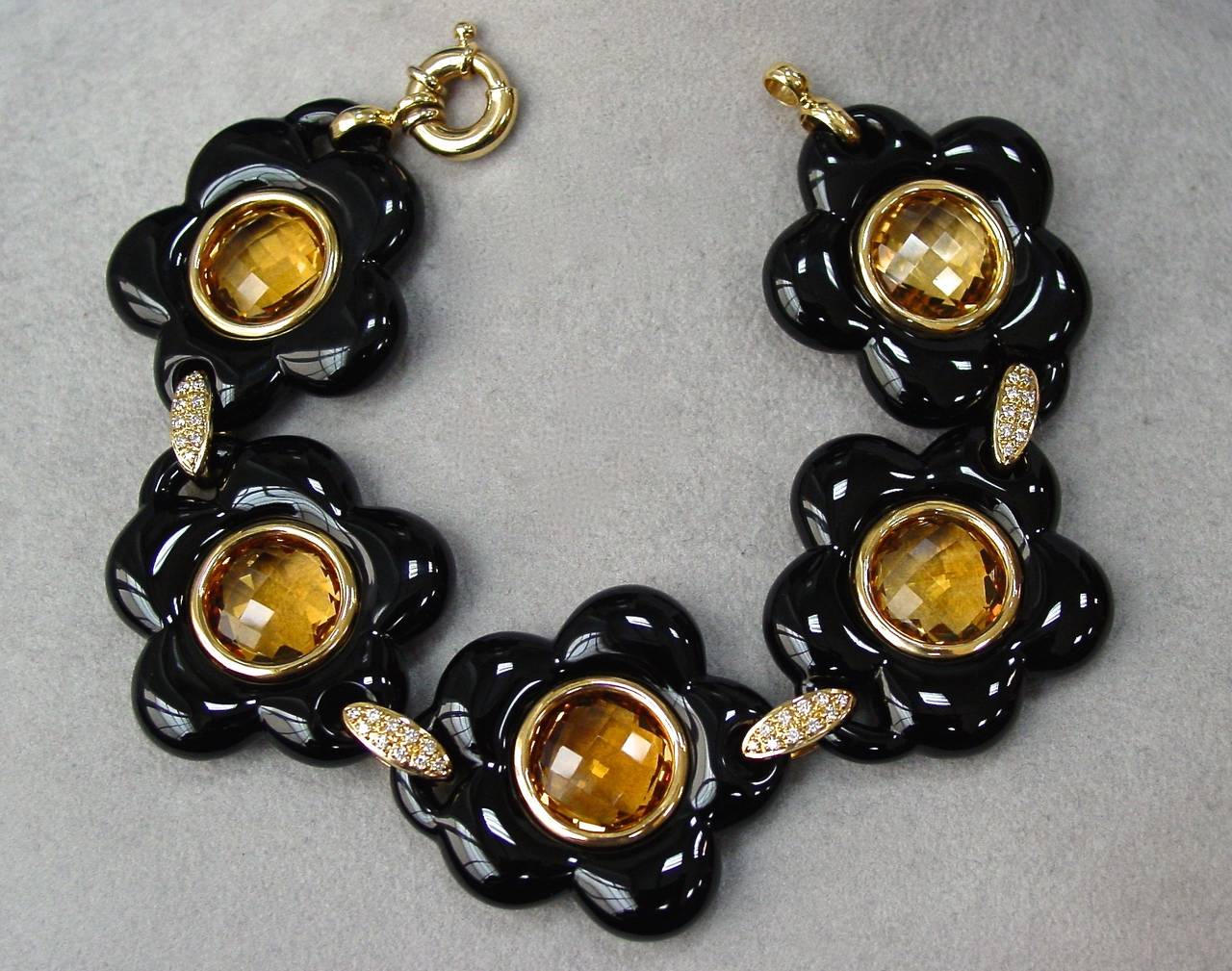 A wonderfully stylish faceted citrine, carved onyx and diamond bracelet mounted in 18 karat yellow gold. Featuring 5 onyx and citrine floral sections connected by  4 diamond links weighing approximately .40 carats.