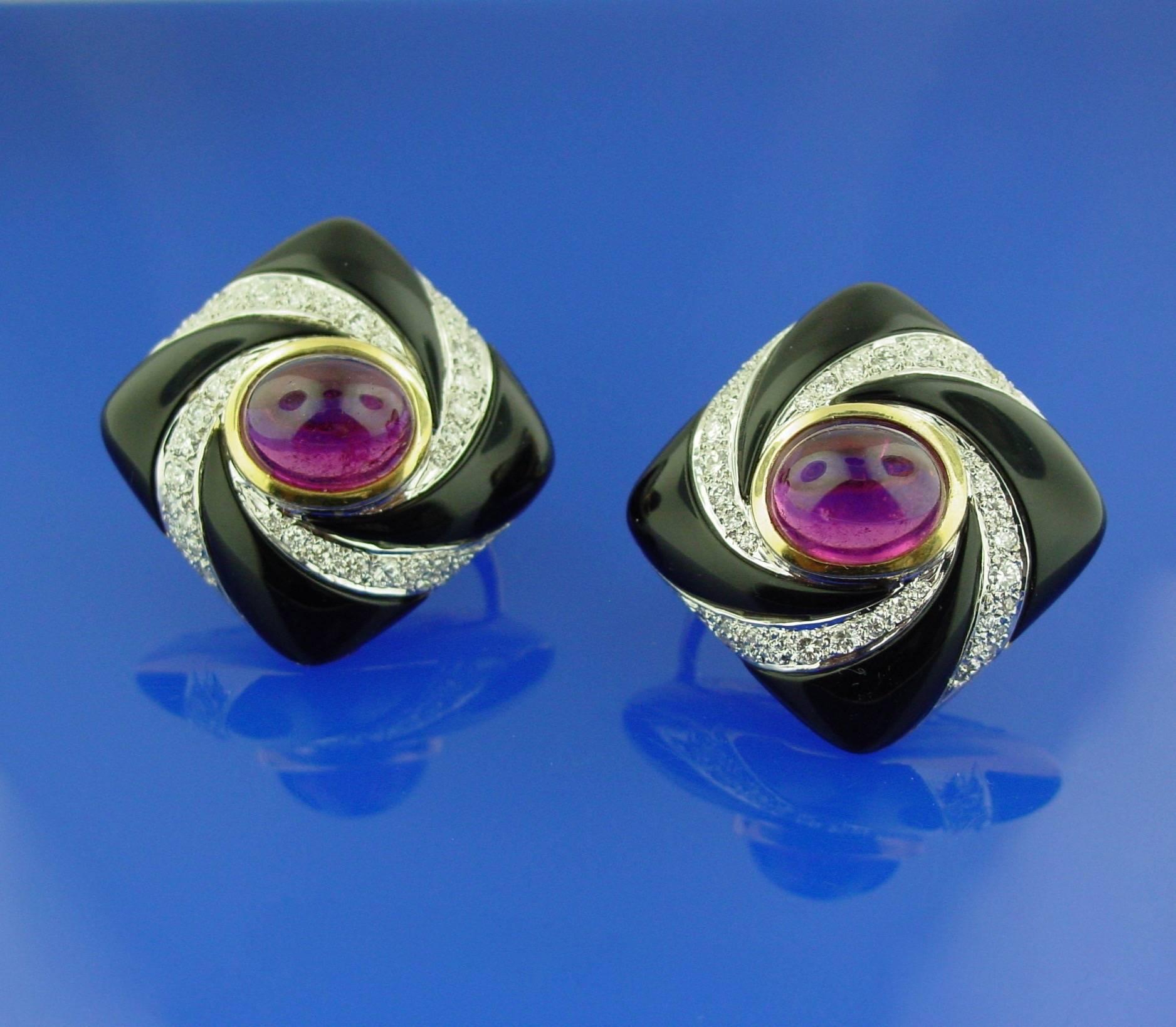 With a lovely pop of tailored color, these earrings feature two oval cabochon pink tourmalines set off by a swirl of diamonds and contrasting black onyx. Mounted in 18 karat yellow gold with post and clip backings.  Approximate diamond weight of 2