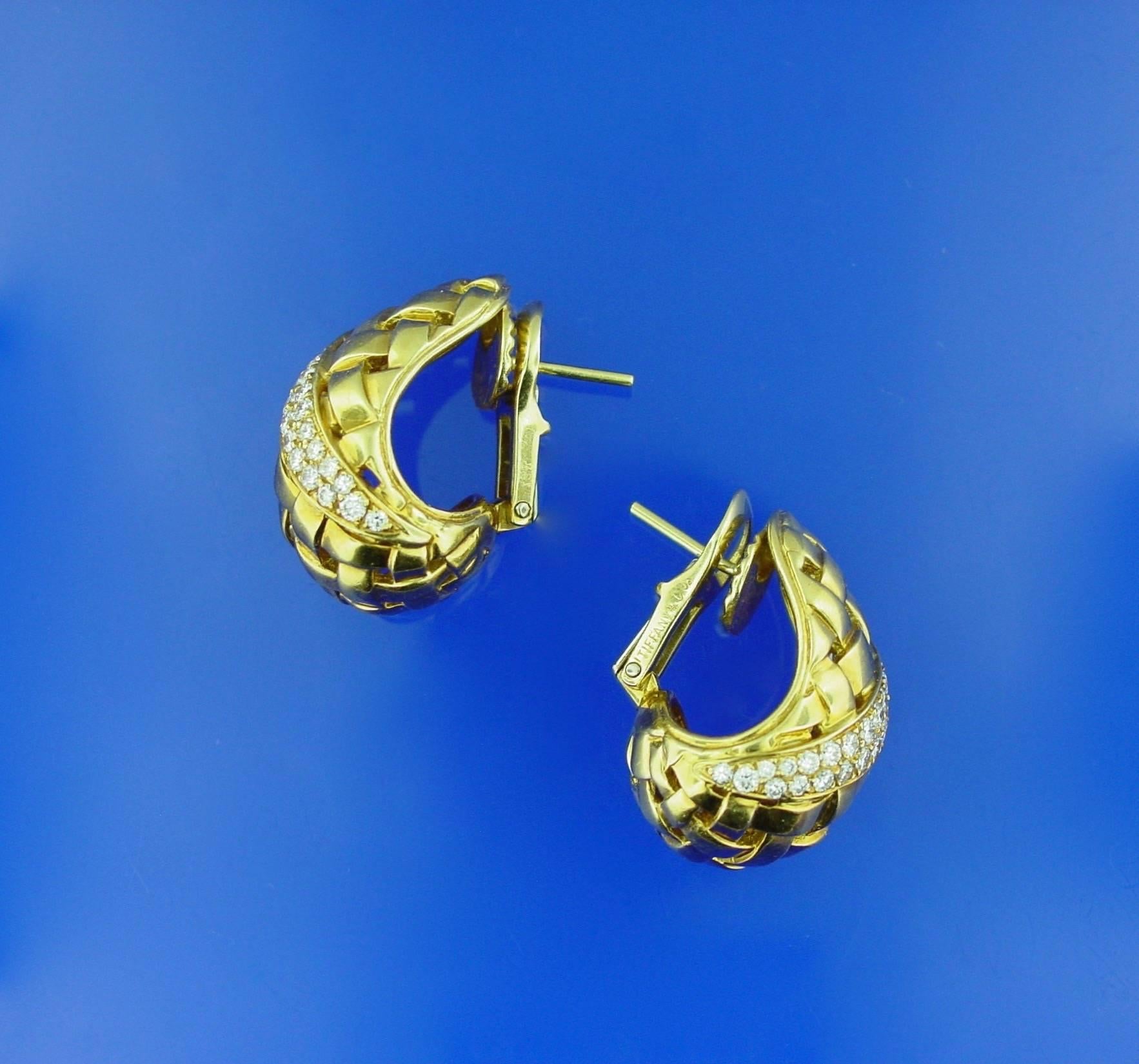 A tailored and classic pair of Tiffany & Co. 18 karat yellow gold basket weave earrings bisected by two rows of round brilliant diamonds weighing approximately one carat in total. 