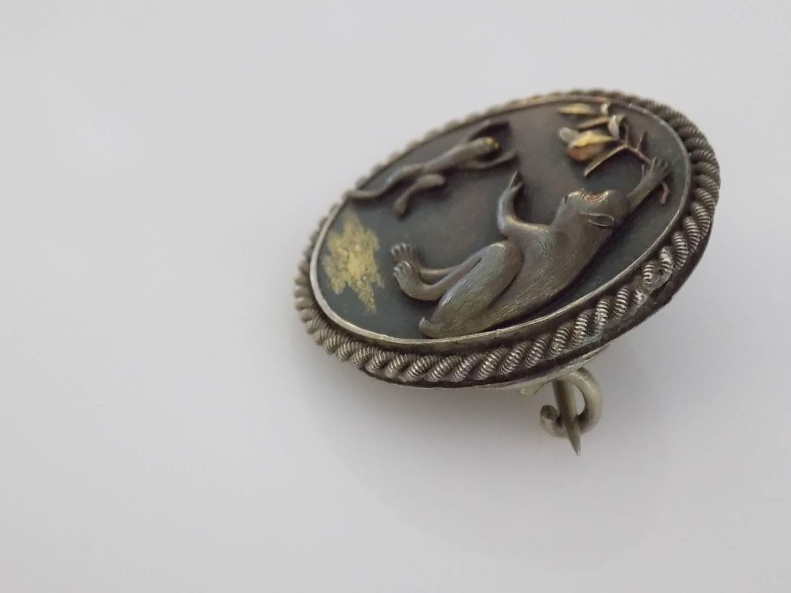 A Stunning Victorian era Japanese Shakudo brooch with an images of monkeys. The mum monkey is teaching her baby to jump to get the fruit on the branch. The brooch made of bronze plaque in silver mount on a white metal backing. Shakudo well know for
