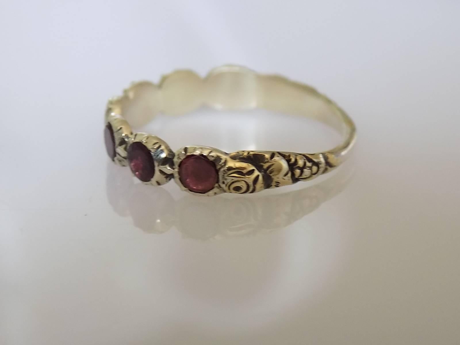 A Lovely Georgian 1700s Gold and seven flat cut Garnet half eternity Ring. Garnets in closed back settings on a beautifully carved with roses and berries shank. English origin. 

Size N 1/2 UK, 6.75 US.

Height of the face 4mm.

Unmarked,