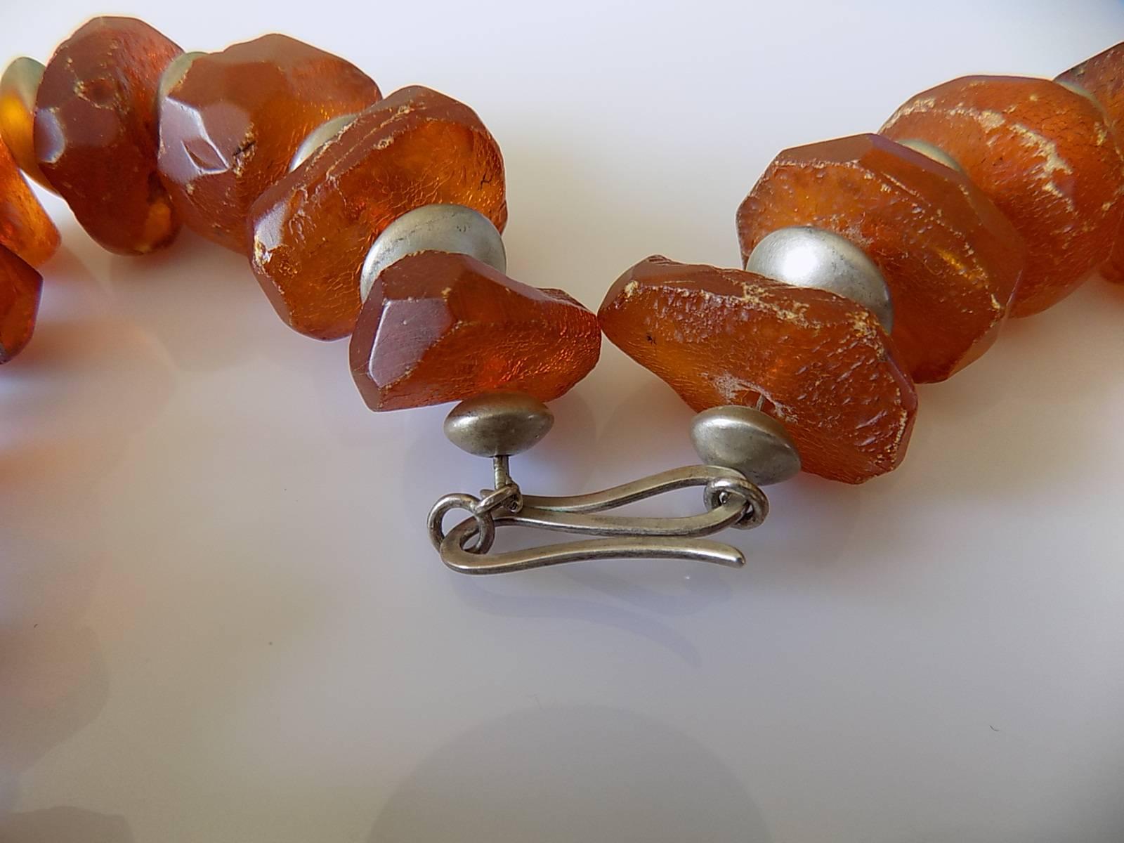 AN IMPRESSIVE ANTIQUE FACETED NATURAL BALTIC AMBER BEADS NECKLACE WITH A SILVER SPACERS BEADS AND SILVER HOOK CLASP.
THE AMBER BEADS WITH A NATURAL INCLUSIONS AND FLAWS.
TOTAL LENGTH INCLUDING CLASP 17 1/4" or 44cm.
LARGE AMBER BEAD 33mm x