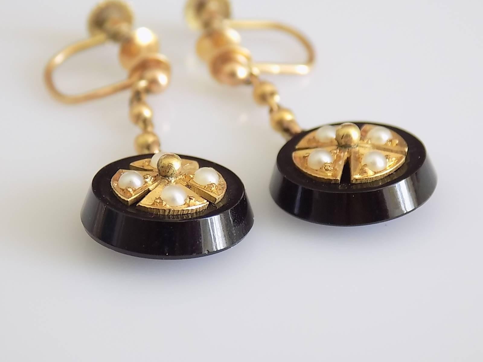 An Antique Victorian era 18 Carat Yellow Gold, Black Onyx and split Natural Seed Pearl Maltese cross Mourning drop earrings. Earrings complete with a working screw backs for unpierced ears.
Total drop 29mm, Width 13mm.
Weight 4.6gr.
Unmarked, tested