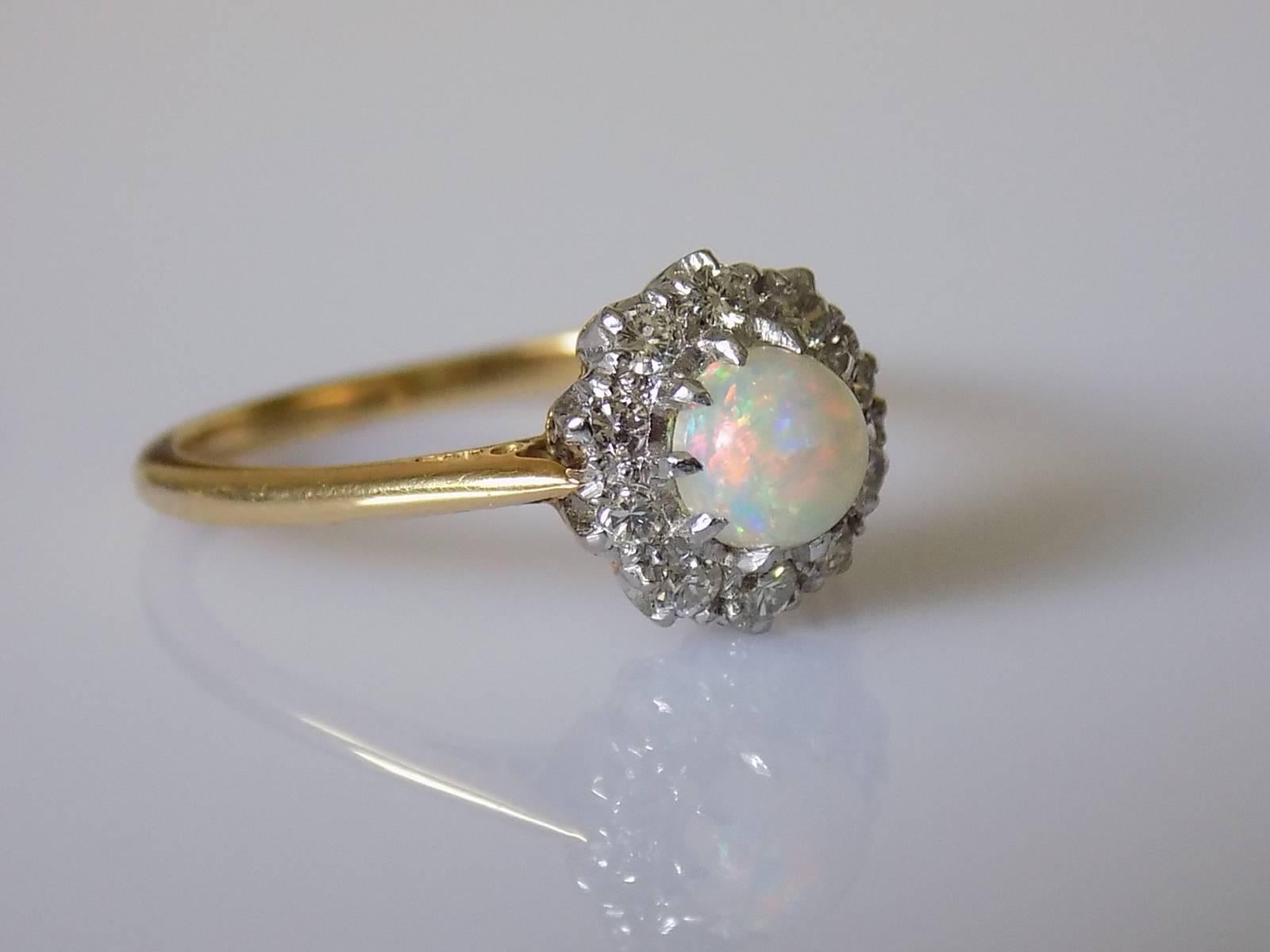 A Gorgeous Edwardian c.1910 18 Carat Gold, fine quality Australian Opal and Diamond cluster ring. English origin.
Size T UK, 10 US.
Height of the face 11mm.
Opal 5.5mm.
Round cut Diamonds approx. 2mm each.
Marked 18CT for 18 carat gold.
Excellent