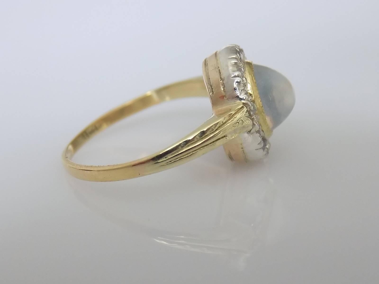 An Edwardian c.1910s timeless classic 18 Carat Gold, Moonstone and old European cut Diamond Halo ring. Diamonds mounted in Platinum setting. 
English origin.
Size O UK, 7.5 US  (sizable). 
Height of the face 12mm. 
Unmarked, tested 18 Carat Gold and