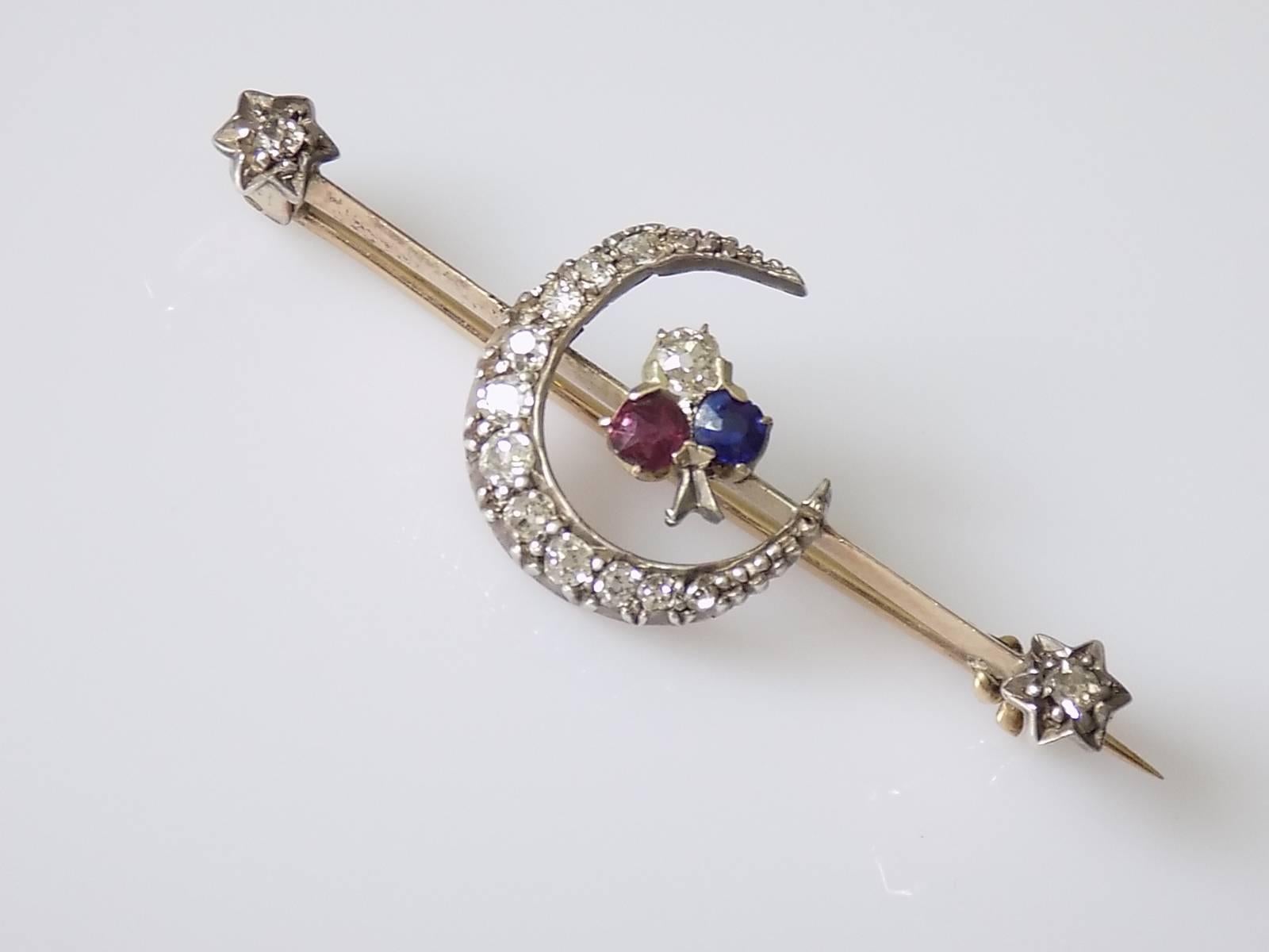 A Beautiful Victorian c.1890s Gold and Silver bar brooch with a Ruby, Diamond and Sapphire clover motive inside of Diamond Crescent and Diamond Stars on the ends. English origin.
Total Length 42mm
Height 16mm
Weight 3.0gr
Unmarked, tested 9 Carat
