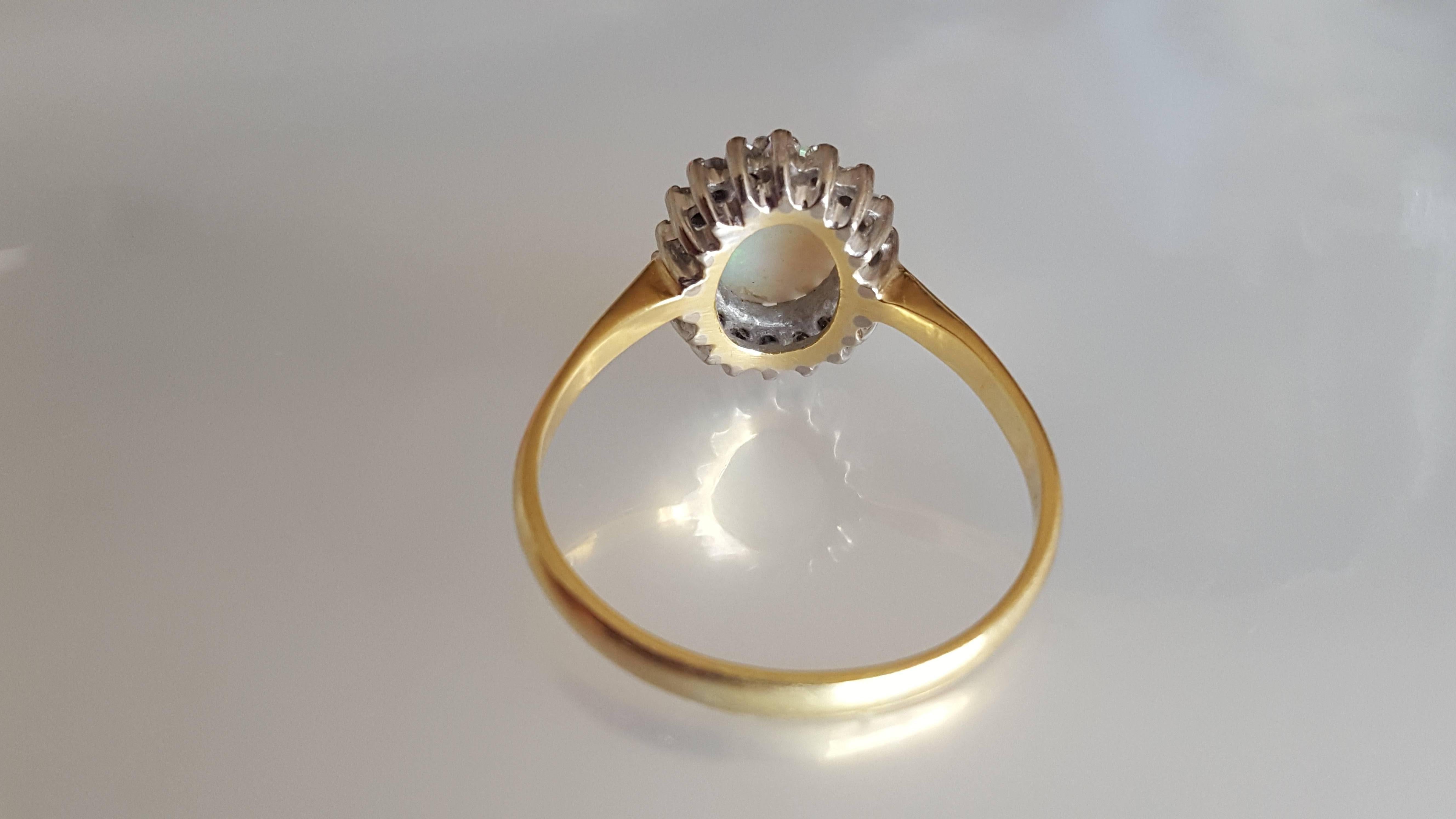 A Lovely Vintage c.1973 Australian Opal and Diamond halo cluster ring in 18 Carat white and yellow gold. English origin. 
Size T 1/2 UK, 10.25 US sizeable 
Height of the face 12mm
Opal 9mm x 7mm
Full London hallmark for 18 Carat Gold, dated