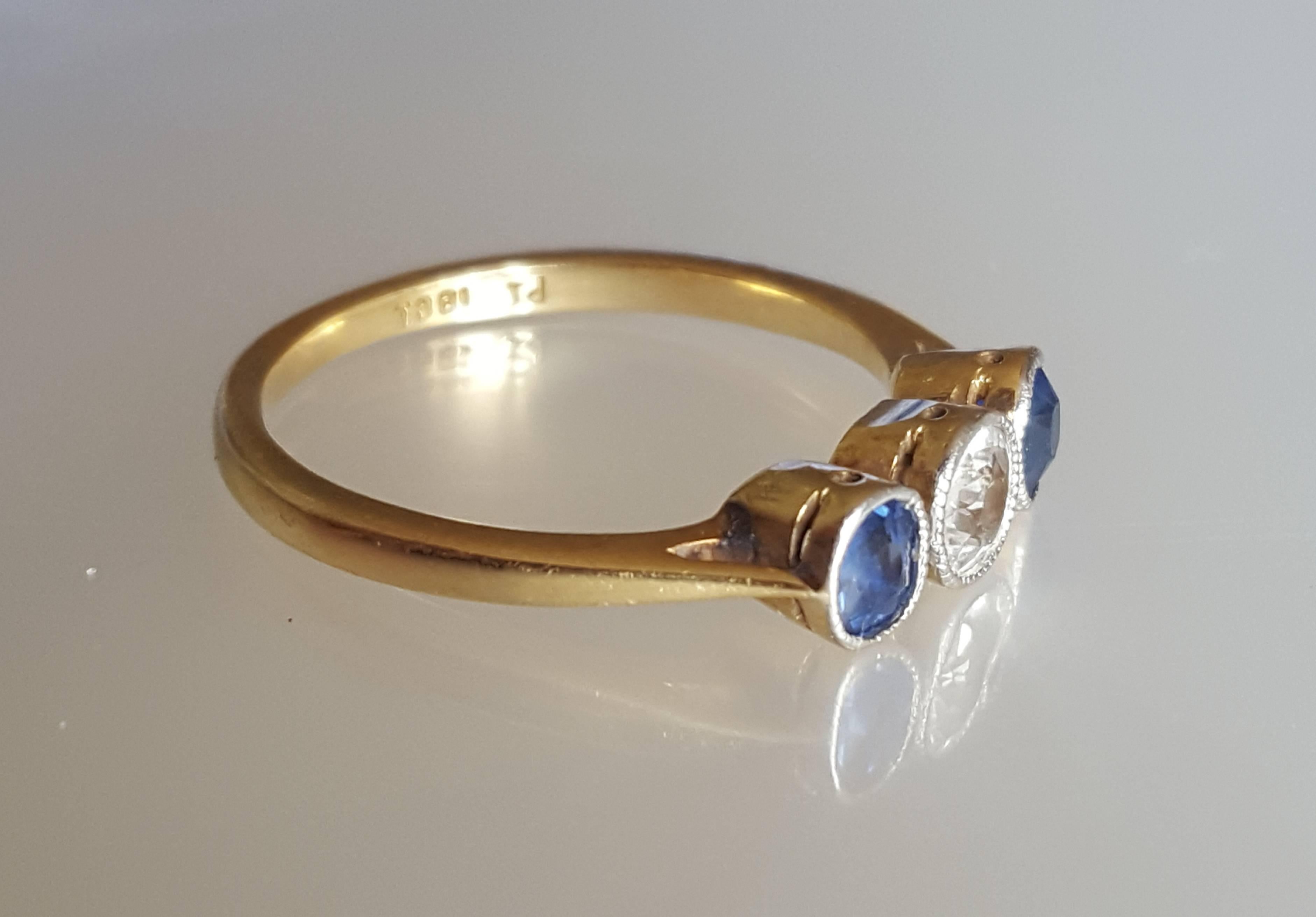A Beautiful Art Deco c.1920s/30s 18 Carat Gold and white/ blue Sapphire trilogy engagement ring.  Sapphire in Platinum topped bezel setting. English origin. 
Size 7.5 US, O UK. 
Height of the face 5mm 
Marked 18CT for 18 Carat Gold. 