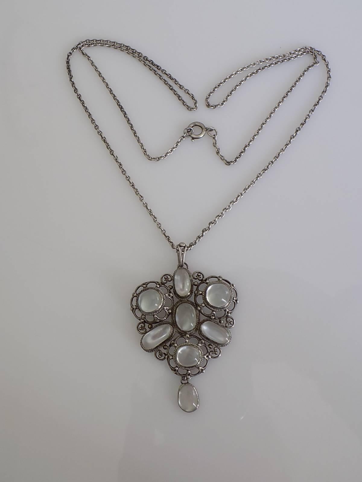 A Beautiful Arts & Crafts c.1920s Sterling Silver and White Moonstone pendant on long Sterling Silver chain. English origin.
Drop of the pendant including bale 60mm, Width 39mm.
Length of the chain including clasp 24