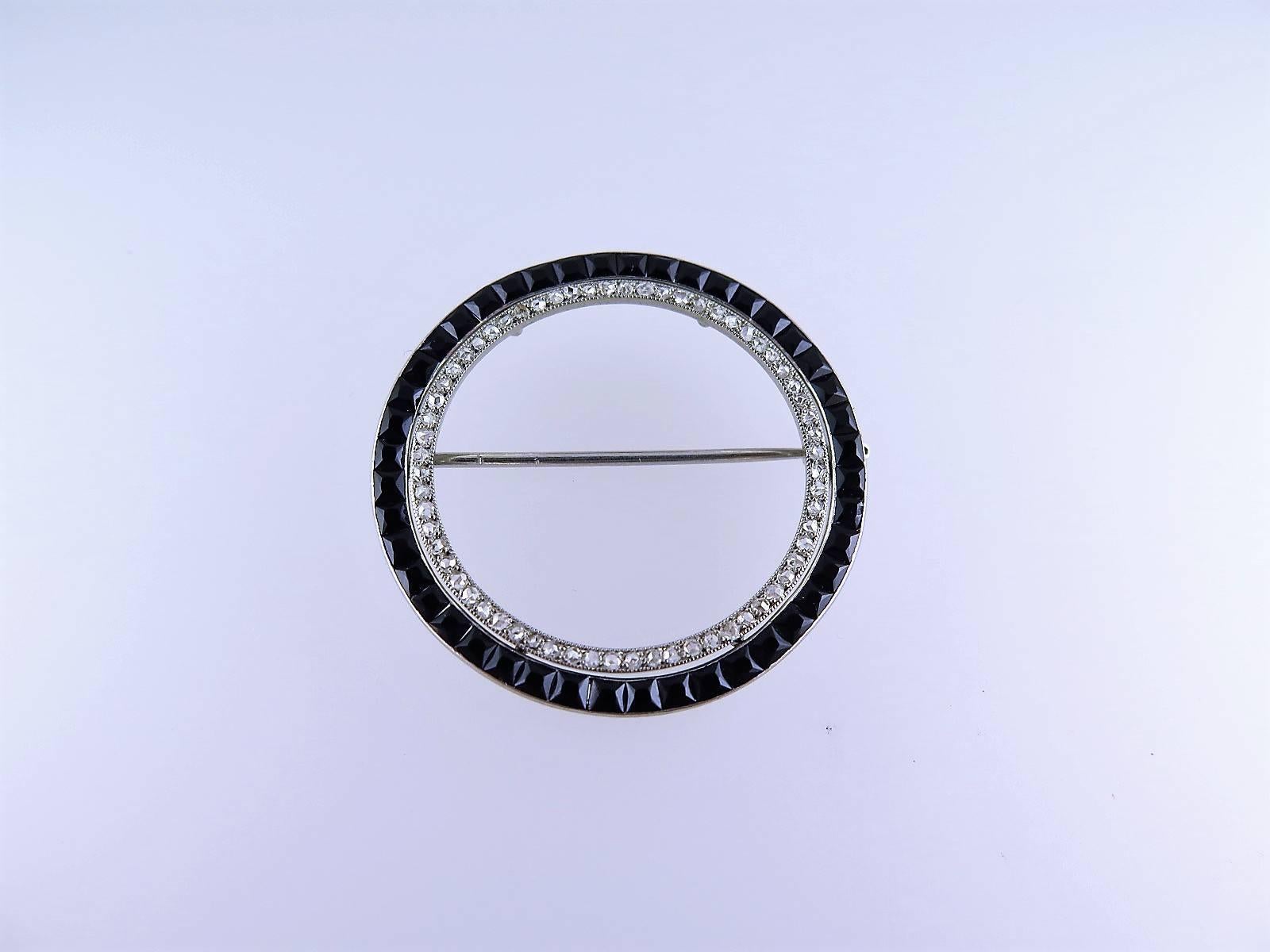Of open circle design, set with two concentric circles of French-cut onyx and rose-cut diamonds, mounted in platinum, signed Cartier Paris Deposé, numbered