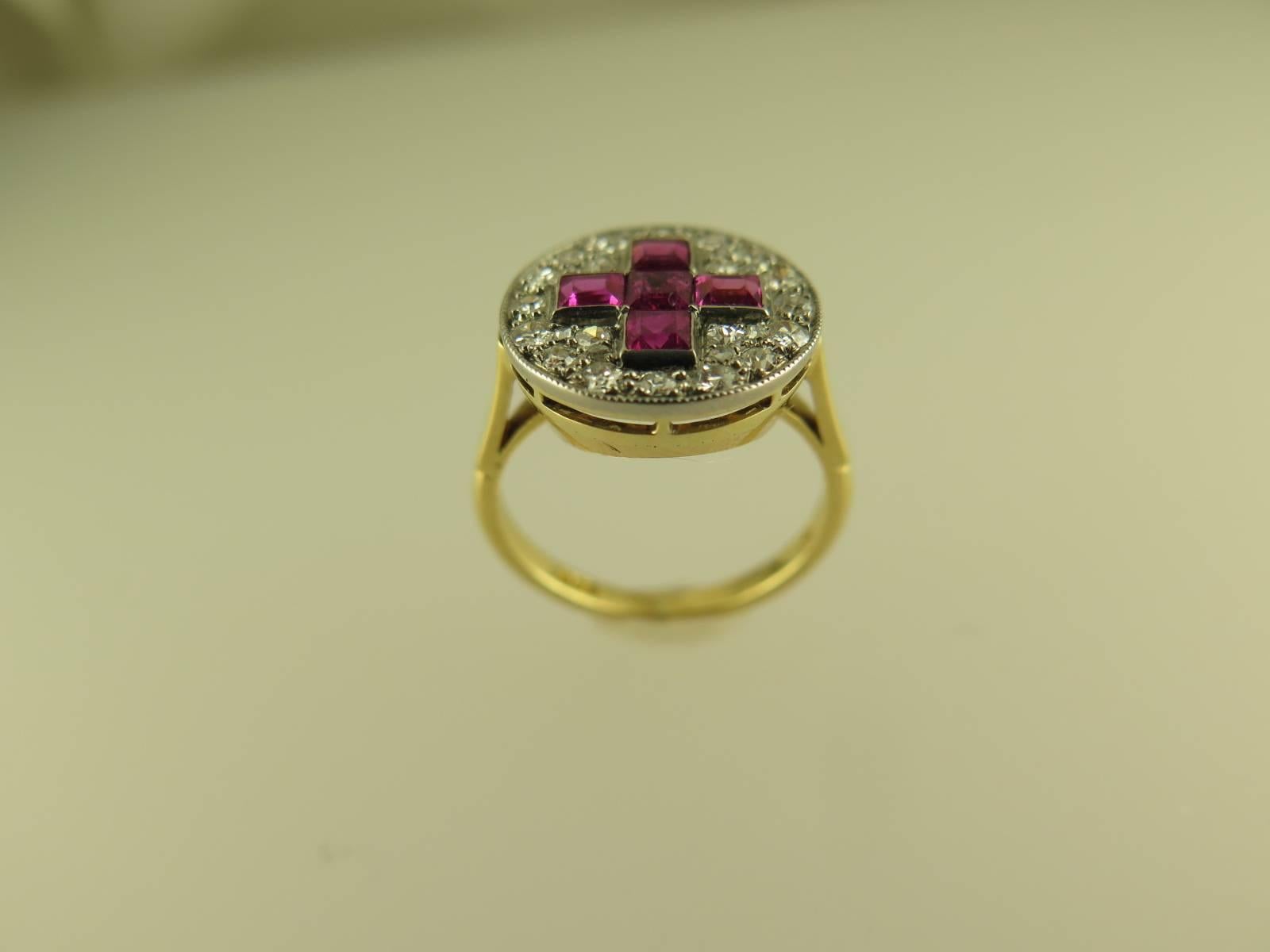 The circular panel pavé-set with approximately 0.85cts of single-cut diamonds and set to the centre with a calibré-cut ruby Greek cross motif, all within a millegrain border, to a plain 18ct yellow gold shank, size J (US size 5), sizeable to order 