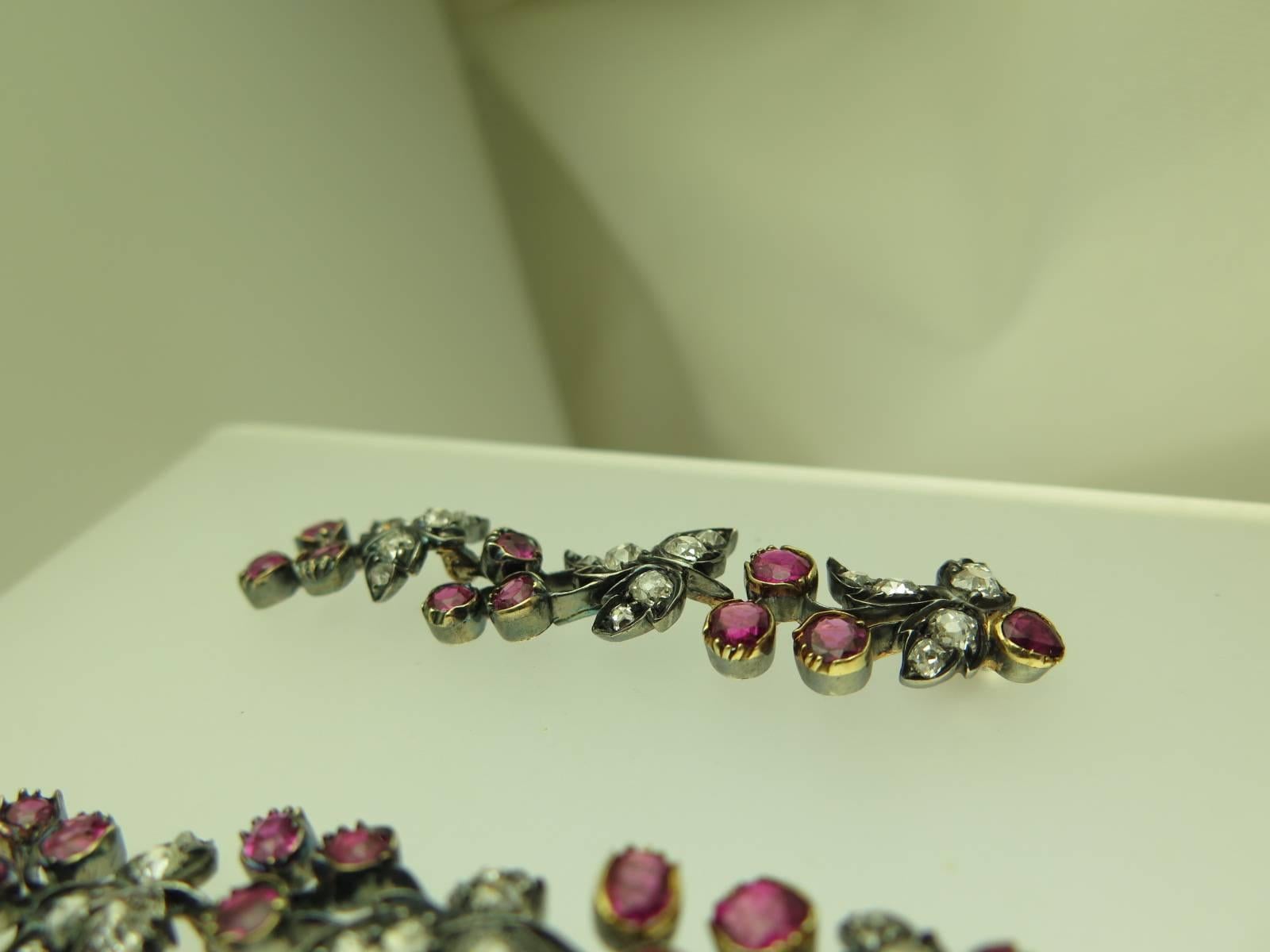 Each pendant earring designed as a fruiting vine set with circular and cushion-shaped rubies and old mine-cut diamonds, mounted in silver and gold, post and butterfly fittings 