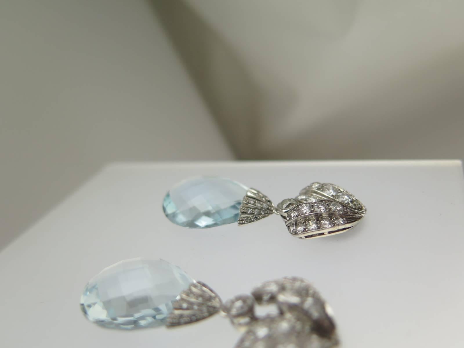 Each pendant earring suspending a drop shaped aquamarine briolette, total weight of aquamarines 20.67cts, from a diamond-set cap and diamond surmounts of leaf design, total weight of diamonds approximately 2.50cts, mounted in 18ct white gold, post