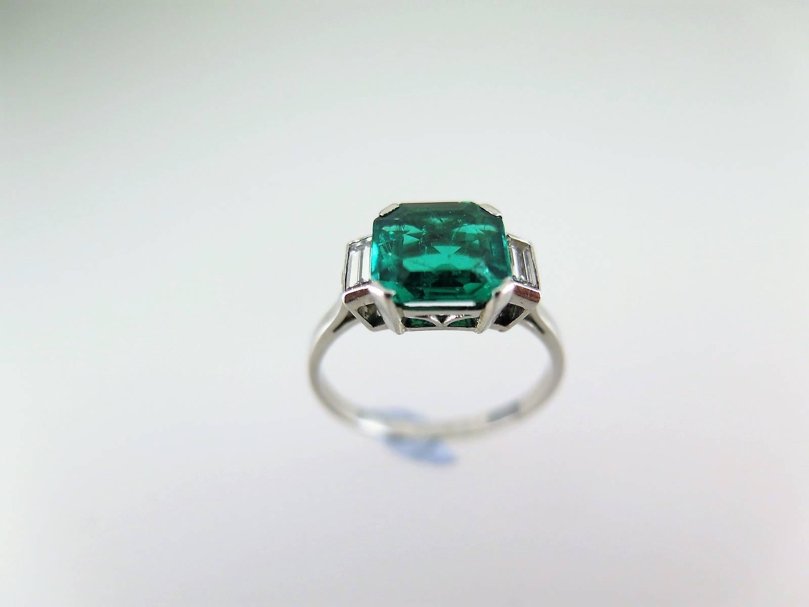 Claw-set with a step-cut emerald weighing 1.93cts between baguette diamond shoulders, mounted in platinum, accompanied by GCS certificate stating that the emerald is Colombian, size P (US size 8), can be resized to order  