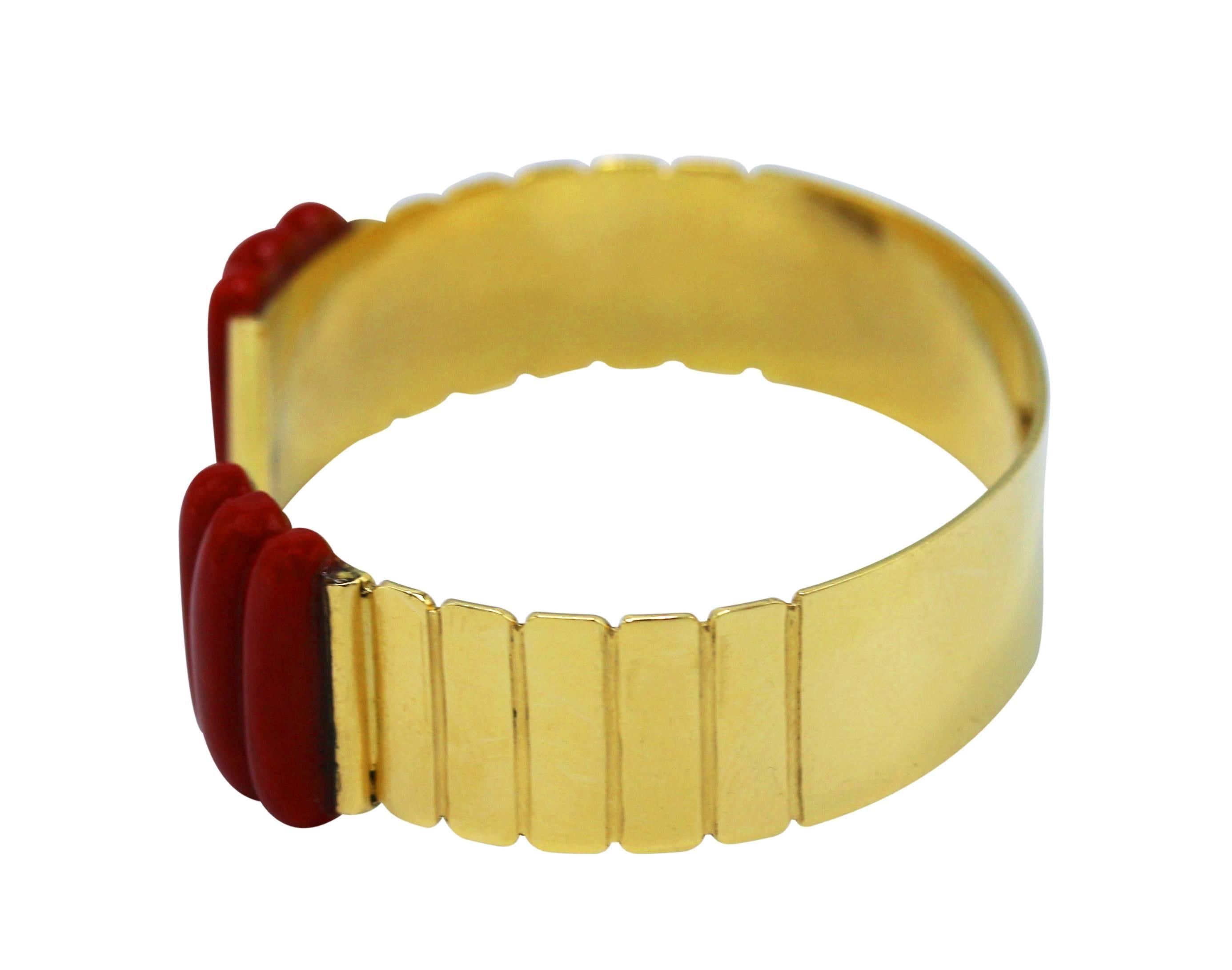 A chic bracelet composed of a polished 18 karat yellow gold cuff with ribbed details accented at the terminals with carved coral segments, length 6 inches, width 1/2 inch, gross weight 31.5 grams, signed Vitali Roma.