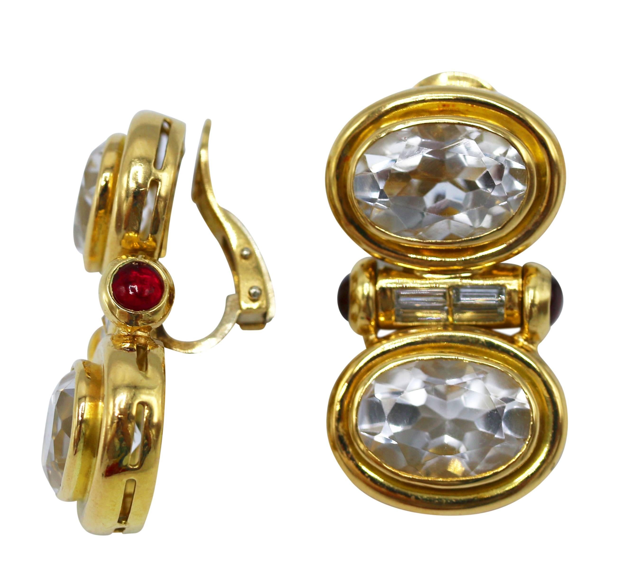 Pair of 18 karat gold, rock crystal, diamond and ruby earclips, large pendants collet-set with 4 faceted oval rock crystals, the center accented by baguette diamonds and cabochon rubies, gross weight 32.5 grams, measuring 1 3/8 by 3/4 inches. Well