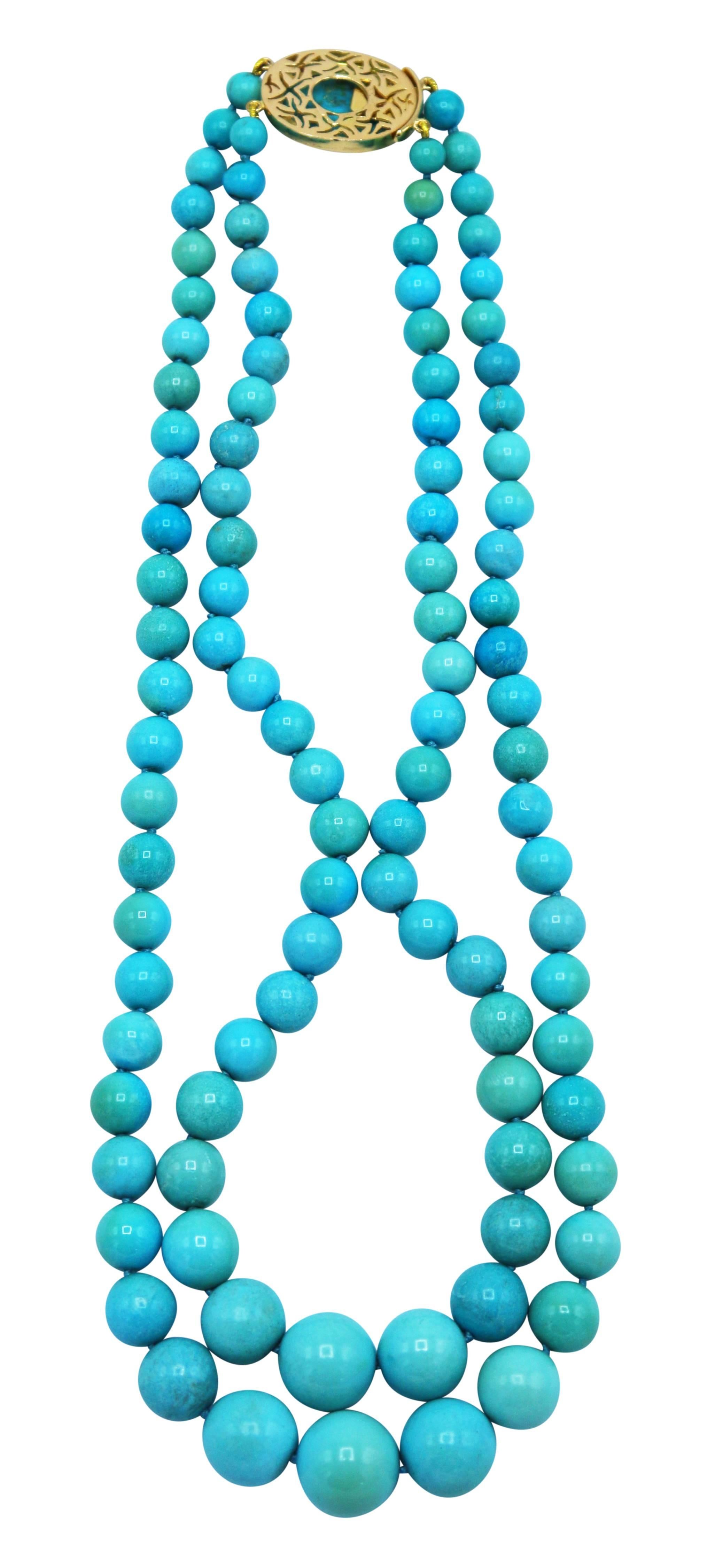 Lovely 18 karat yellow gold and natural turquoise necklace, circa 1970, designed as two graduated strands of numerous natural turquoise beads measuring 15.0 to 7.0 mm., completed by an oval clasp set with a cabochon turquoise segment framed by round