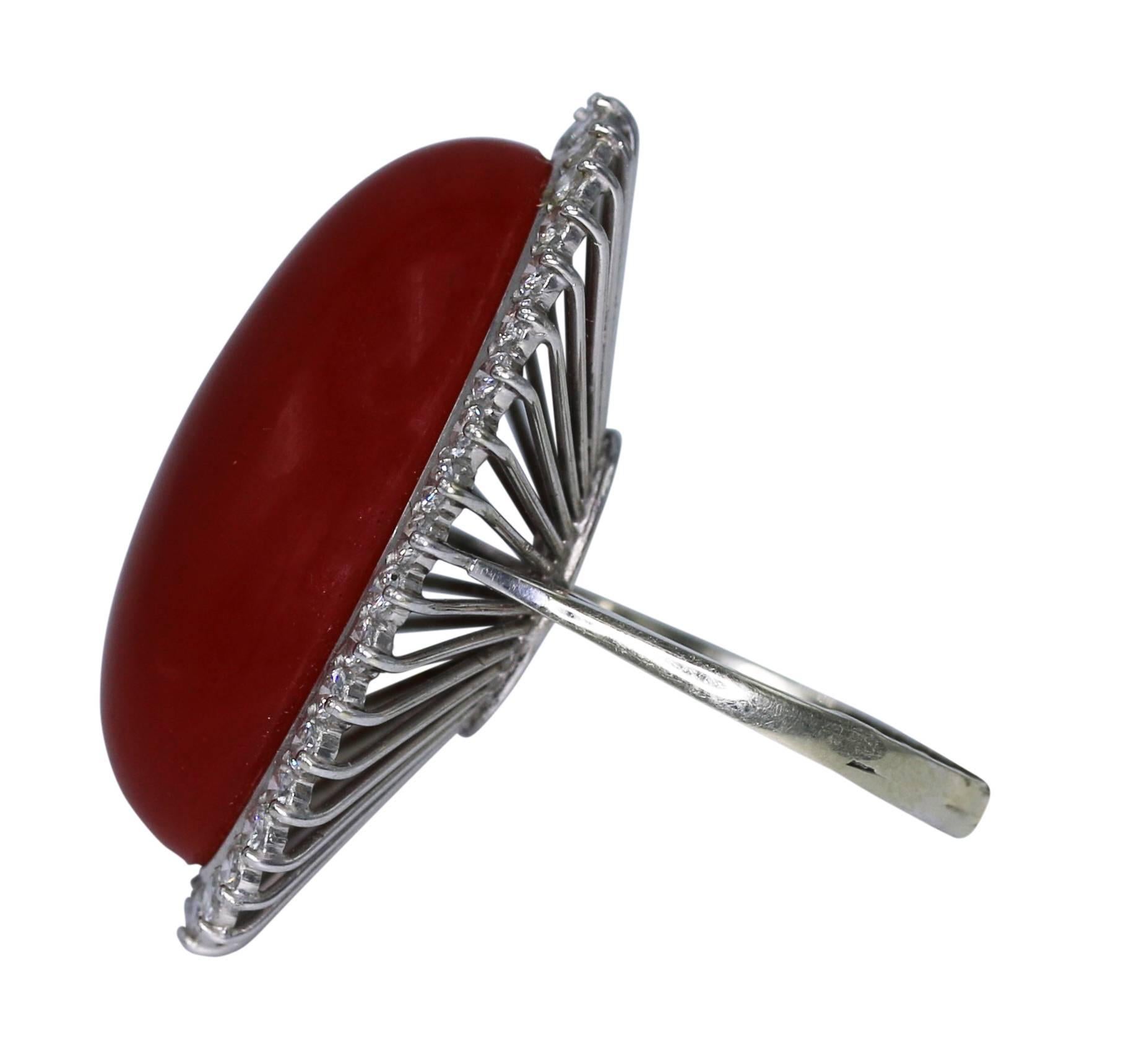 18 karat white gold, natural coral and diamond ring, set in the center with a natural dark red oval coral cabochon, framed by round diamonds weighing approximately 1.10 carats, size 6 1/2, measuring 1 1/4 by 1 by 1 1/2 inches. Accompanied by GIA