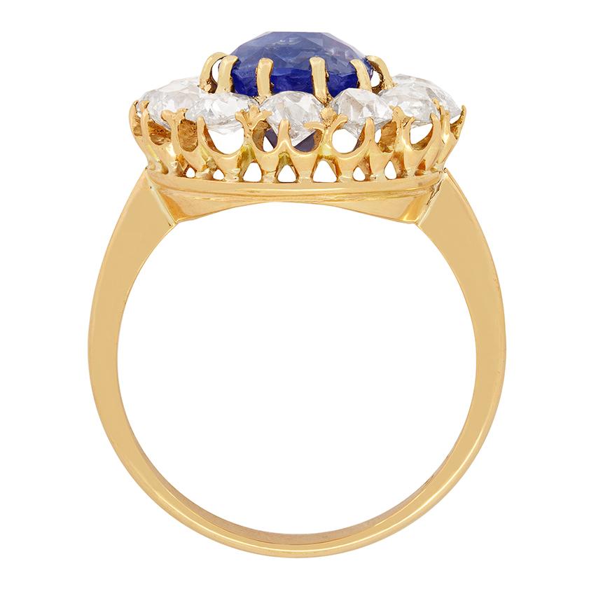 A stunning 3.55 old cushion cut Sapphire sits central to this halo ring from the Victorian Era. The sapphire is firmly claw set into an intricate ring hand crafted from 18 carat rose gold. It is then surrounded by a halo of twelve old cut diamonds