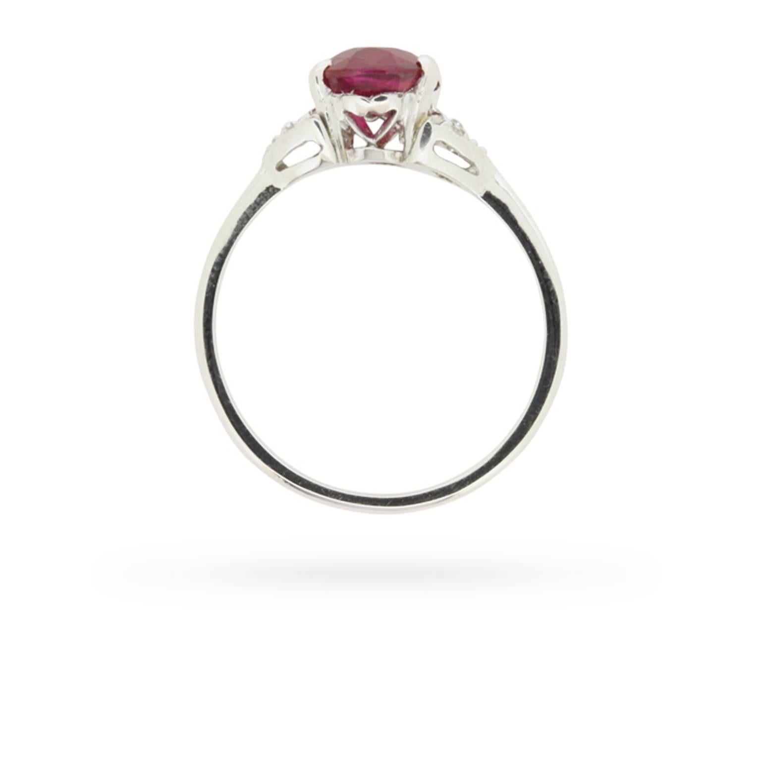 A ripe, red, GIA certified, oval-shaped ruby is the star of this original 1930s era platinum, ruby, and diamond ring.

The stunning 2.03 carat stone is resplendent in four curving claws set within a handmade gallery between a sparkling trefoil