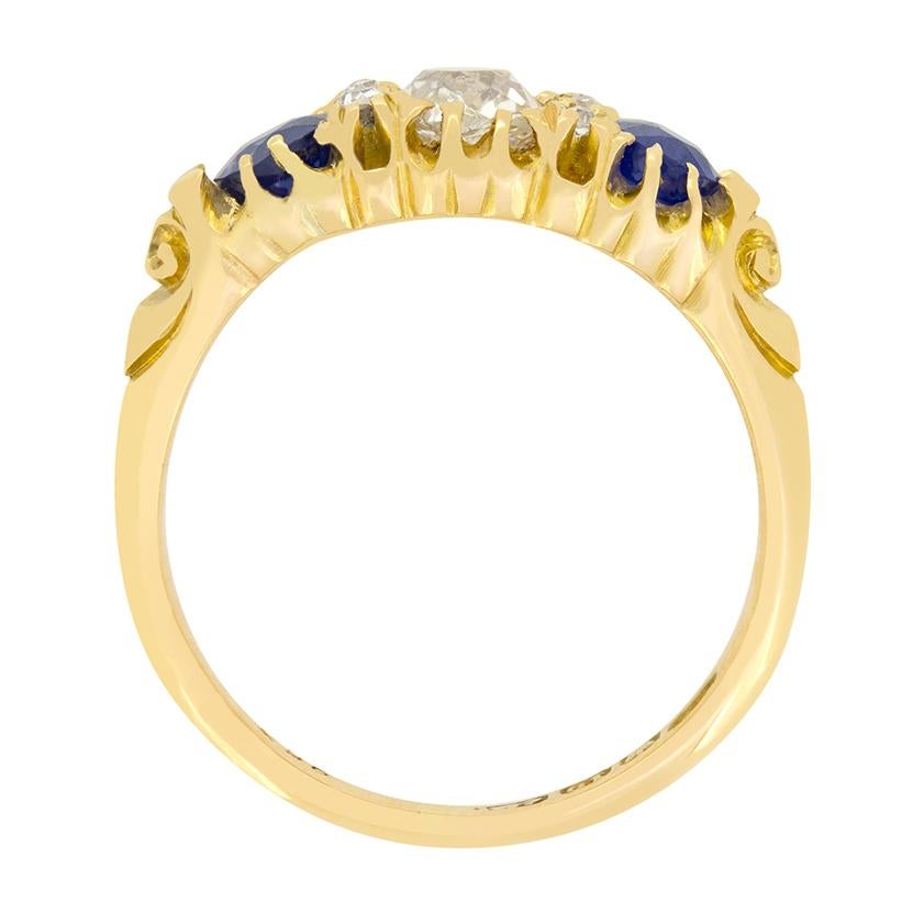 Un seul diamant ancien de taille coussin est flanqué de deux magnifiques saphirs dans cette bague victorienne classique à tige sculptée. Le diamant central pèse 0,60 carat et présente une couleur G et une pureté VS1. Chacun des saphirs qui