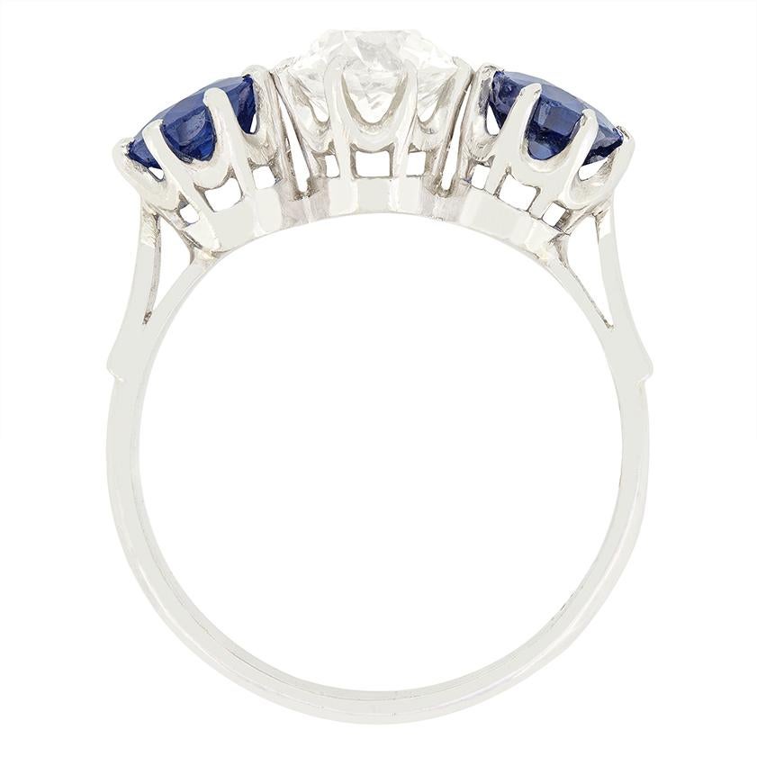 Uno scintillante diamante vecchio taglio si trova tra due zaffiri naturali in questo splendido anello trilogy Art Deco. Il diamante centrale da 1,30 carati è una pietra di taglio antico con colore H e purezza VS2. Gli zaffiri laterali hanno un