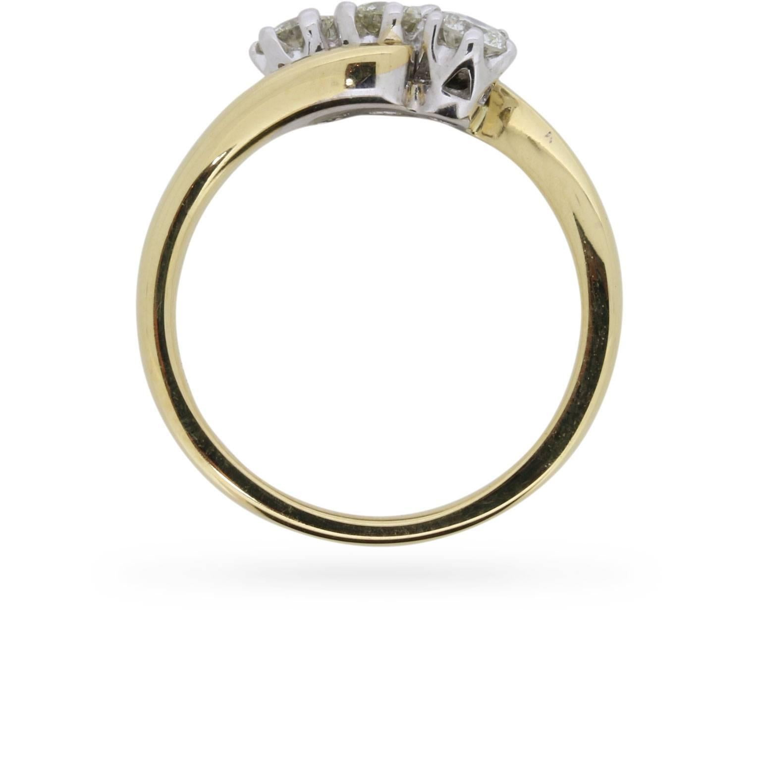 Three round brilliant cut diamonds are set on the bias in 18 carat white gold at the centre of this predominantly 18 carat yellow gold engagement ring dating from the 1970s.

Gemstone: Diamond
Carat Weight: 0.60
Stone Shape: Round Brilliant
Colour: