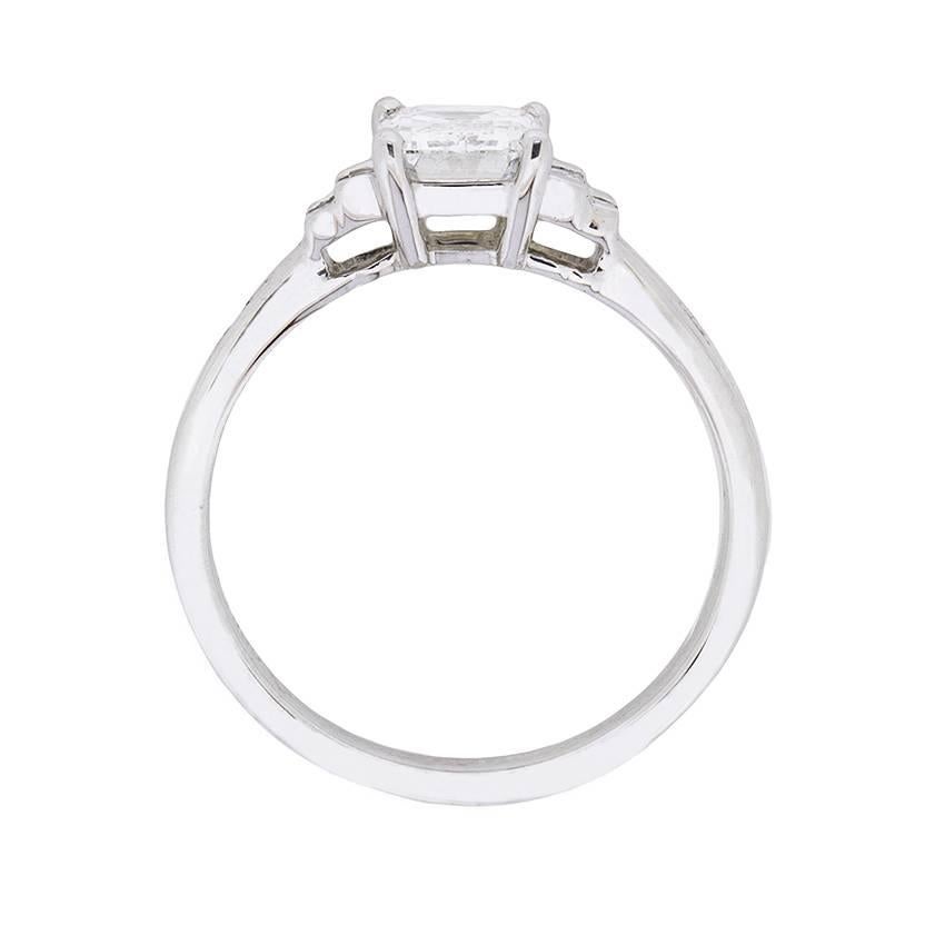 This wonderfully geometric engagement ring is classically art deco. The centre stone, which has a certificate to confirm colour and clarity from GIA, is stunning within a matching and mesmerising mount. The Emerald cut diamond has a weight of 0.95