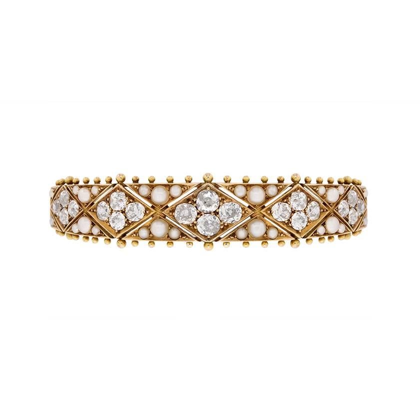 This unique and stunning bangle dates back to the Victorian era, around 1870. It is made out of 18 carat yellow gold and features a display of diamonds and pearls. The diamonds are old cuts, and would have been cut by hand. They have a total weight