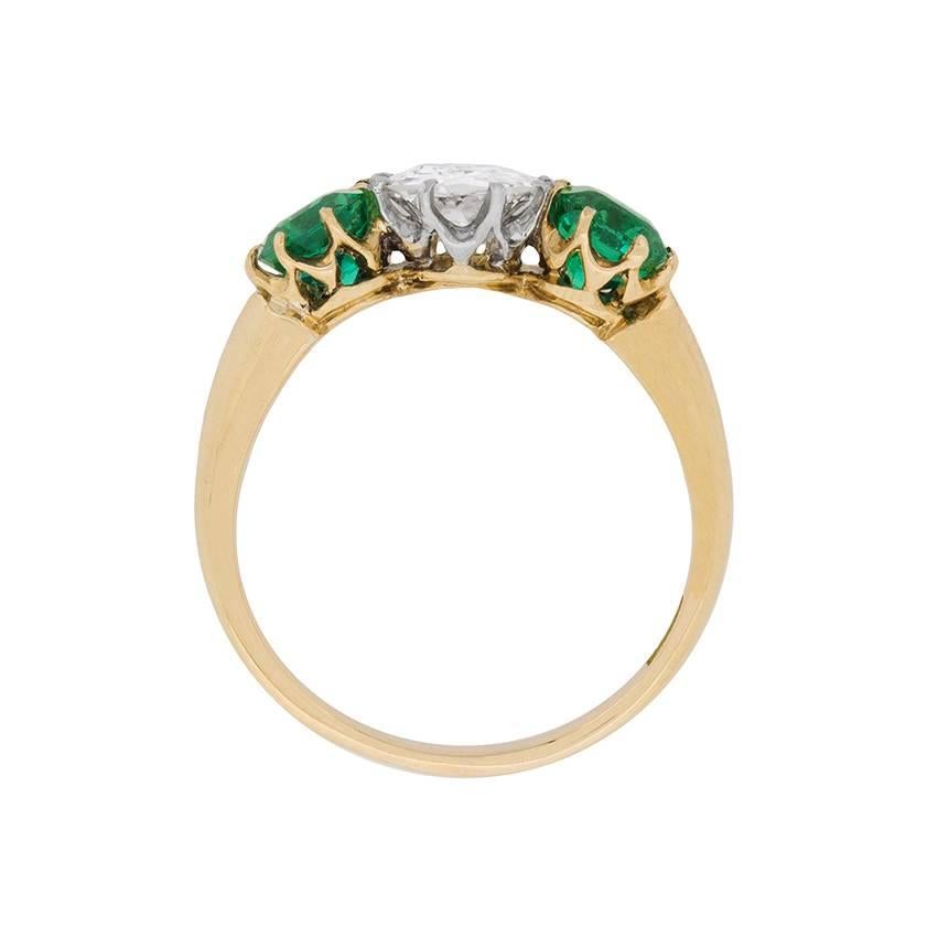 A simply stunning Edwardian three stone ring, highlighting a wonderful old cut diamonds, supported by luscious green emeralds on either side. The diamond weighs 0.75 carat and is an estimated G in colour and VS2 in clarity. The emeralds are natural,