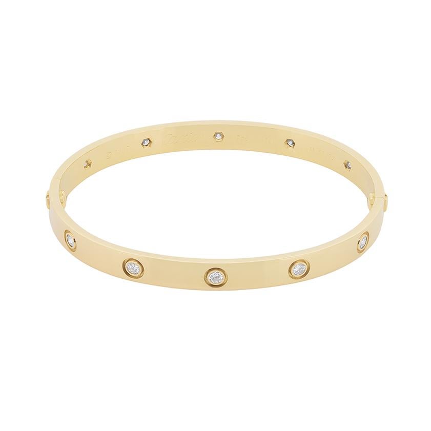 A Cartier Love Bangle, featuring 10 rub over set diamonds within 18 carat yellow gold. It is in as good as new condition and has all original makers marks. The diamonds which are set expertly along the bangle are F in colour and VVS in clarity. They