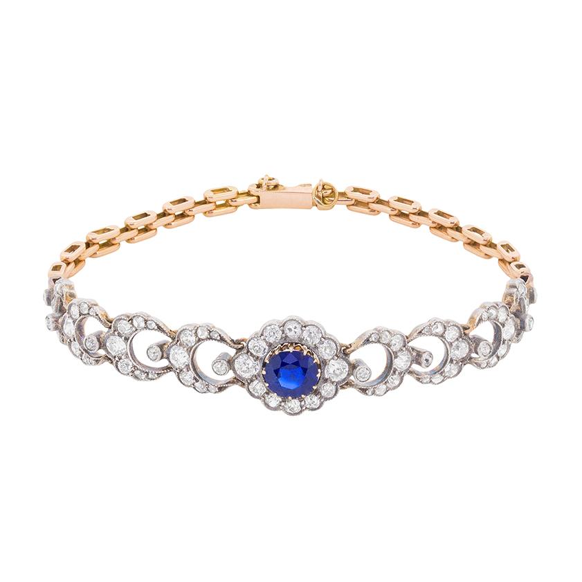 This stunning Edwardian bracelet features a claw set central sapphire which is an impressive blue. The natural gemstone weighs 1.35 carat and has no evidence of heat treatment. It is beautifully surrounded by a halo of old cut diamonds totalling to