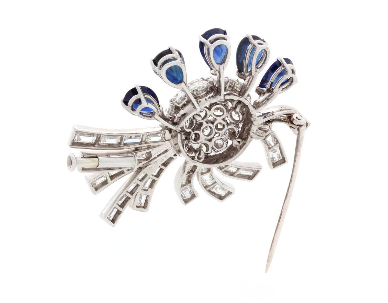 Art Deco platinum diamond and sapphire brooch. Brooch center in multiple round diamonds, surrounded by five tear drop blue sapphires on one side and ten baguette diamond ribbons on the other. Brooch Diamensions: Length 1.88