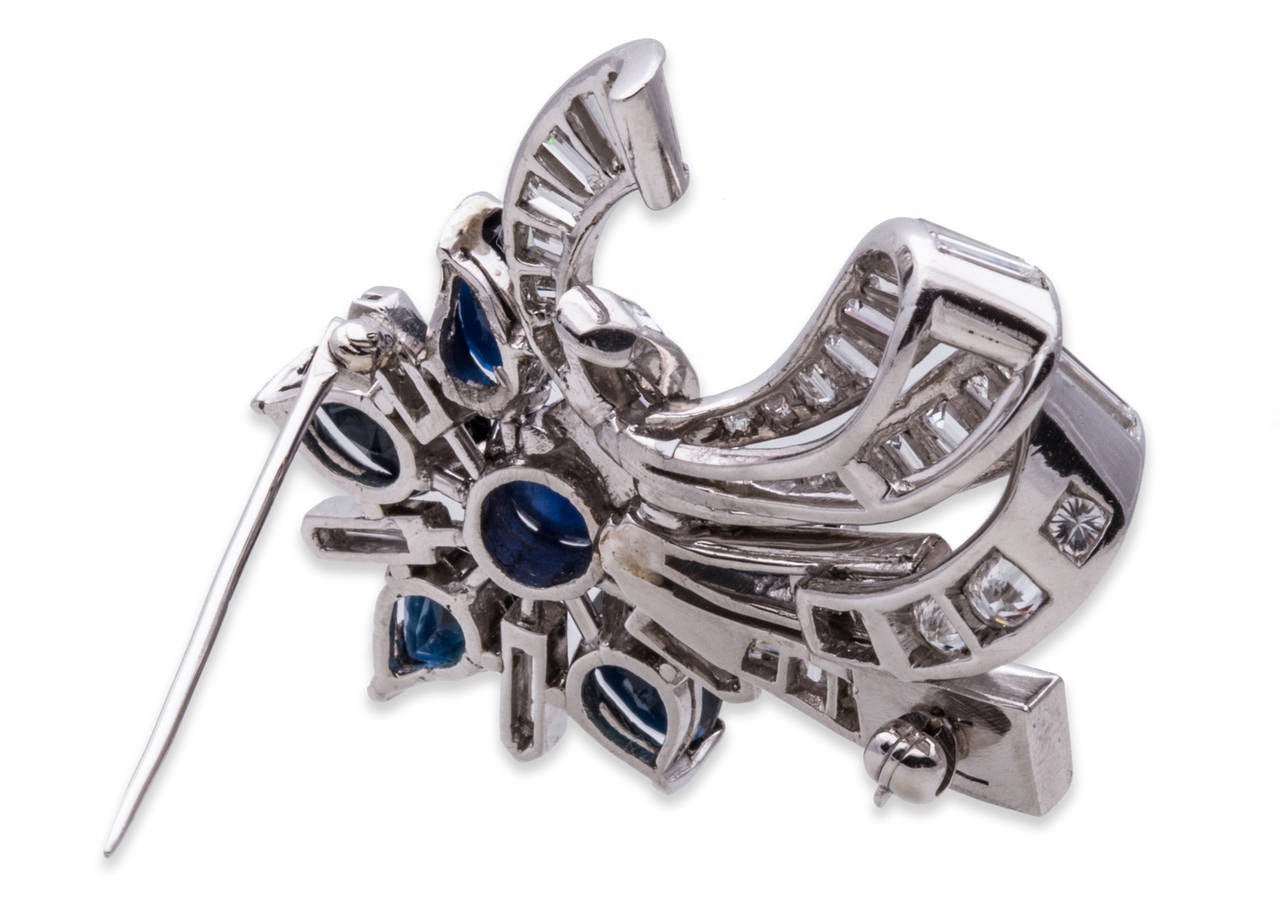 Diamond and Sapphire Flower and Ribbon Brooch Pendant in 18K White Gold. Cabochon Sapphire Flower Center, Tear Drop Sapphires & Diamond Baguette Petals, Accented by a Brilliant & Baguette Diamond Ribbon. Can be worn as a brooch or as a pendant.