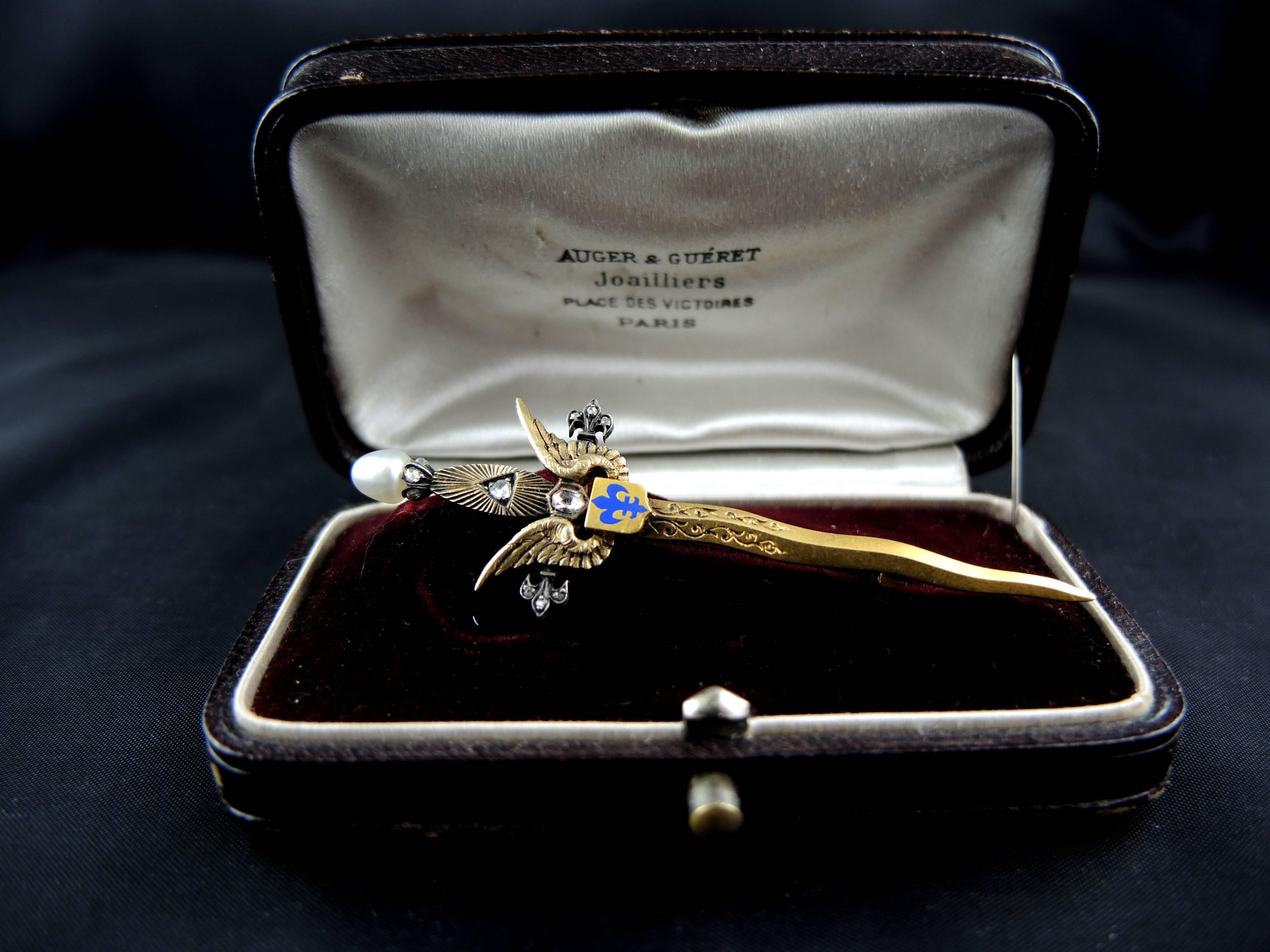 Vermeil (gold plated silver) royalist sword brooch, decorated with an enameled fleur-de-lys, and set with rose cut diamonds, total weight estimated around 0,15ct, and a natural pearl.

Sold with its original bow, signed by Auger et Guéret, jeweller