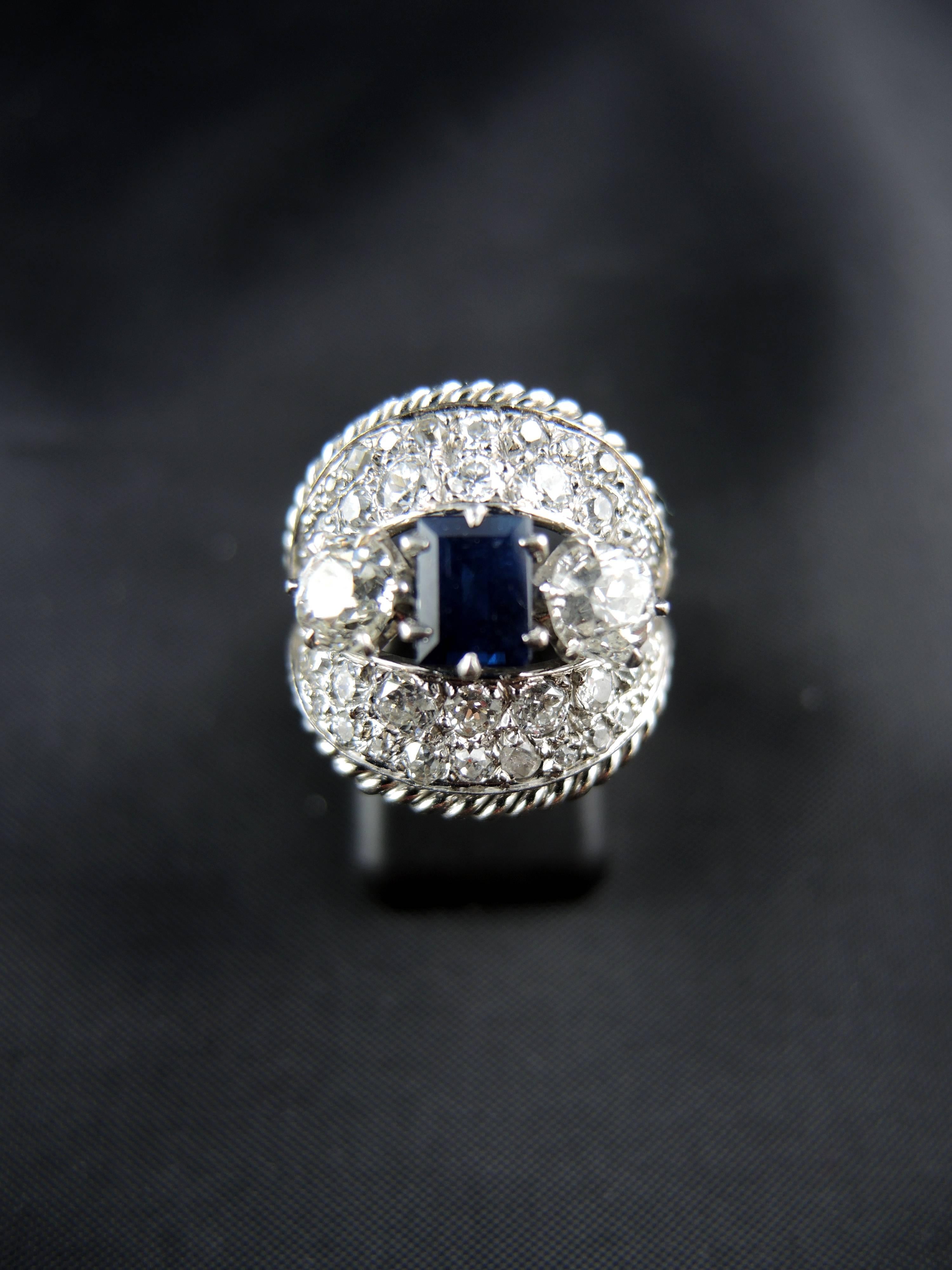 18kt white gold and platinium ring (quality mark: eagle's and dog's head) with a central sapphire, weight around 0,70ct, and old cut diamonds, which total weight is estimated around 1,70ct.
Circa 1960.

Weight: 9,30g
Ring size: 53 (diameter 16,80/