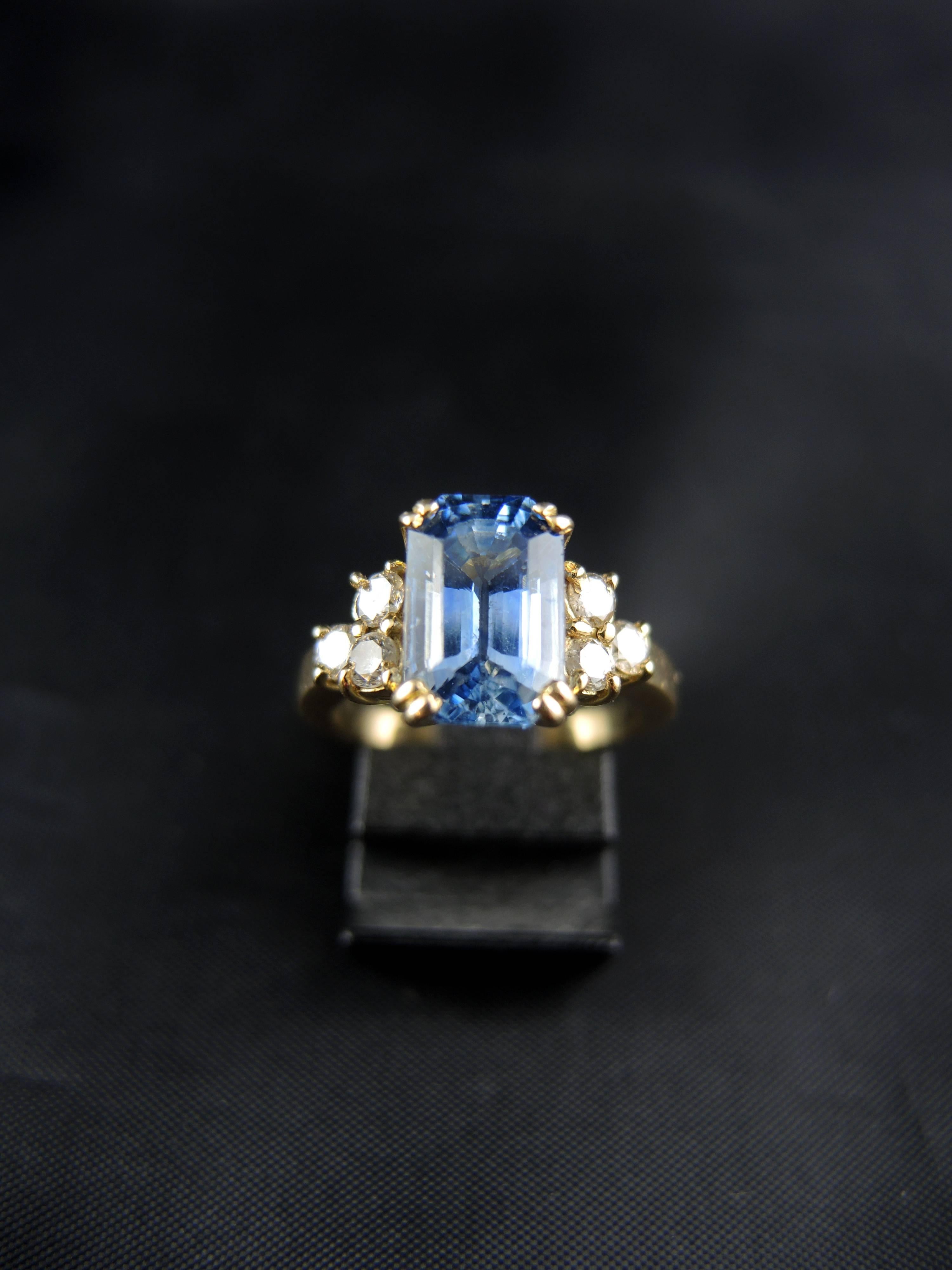 Yellow gold engagment ring (quality mark: head of eagle) set with a central emerald cut sapphire (certainly from Sri Lanka), weight estimated around 3.80 Ct, with modern brillant cut diamonds, which total weight is estimated around 0,40 Ct.

French