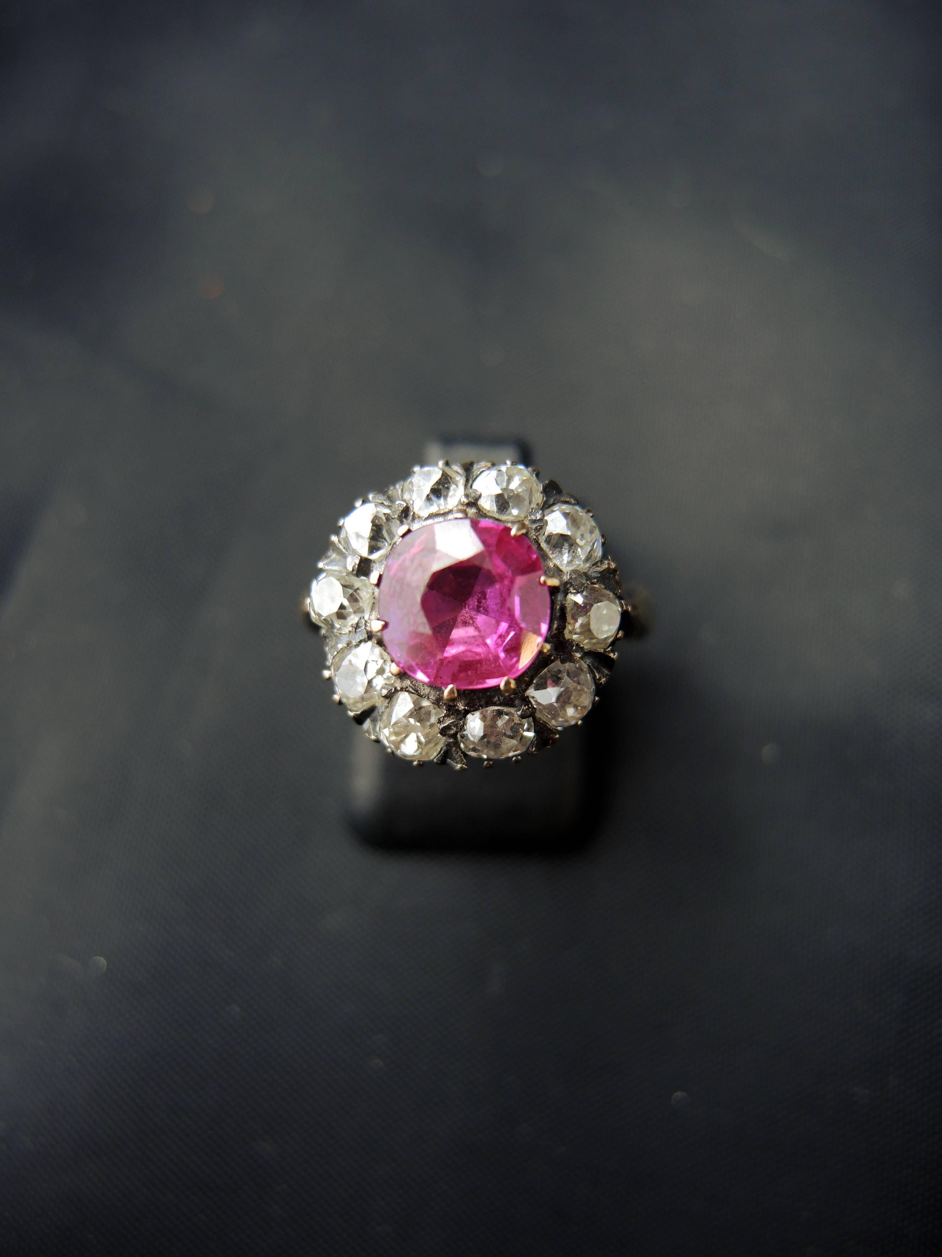 18kt rose gold and silver engagment Victorian cluster ring (quality mark: owl) set with a red stone (synthetic ruby) surounded with old cut diamonds.
Total diamonds weight estimated for around 1,30 Ct. 

Victorian work from the mid 19th