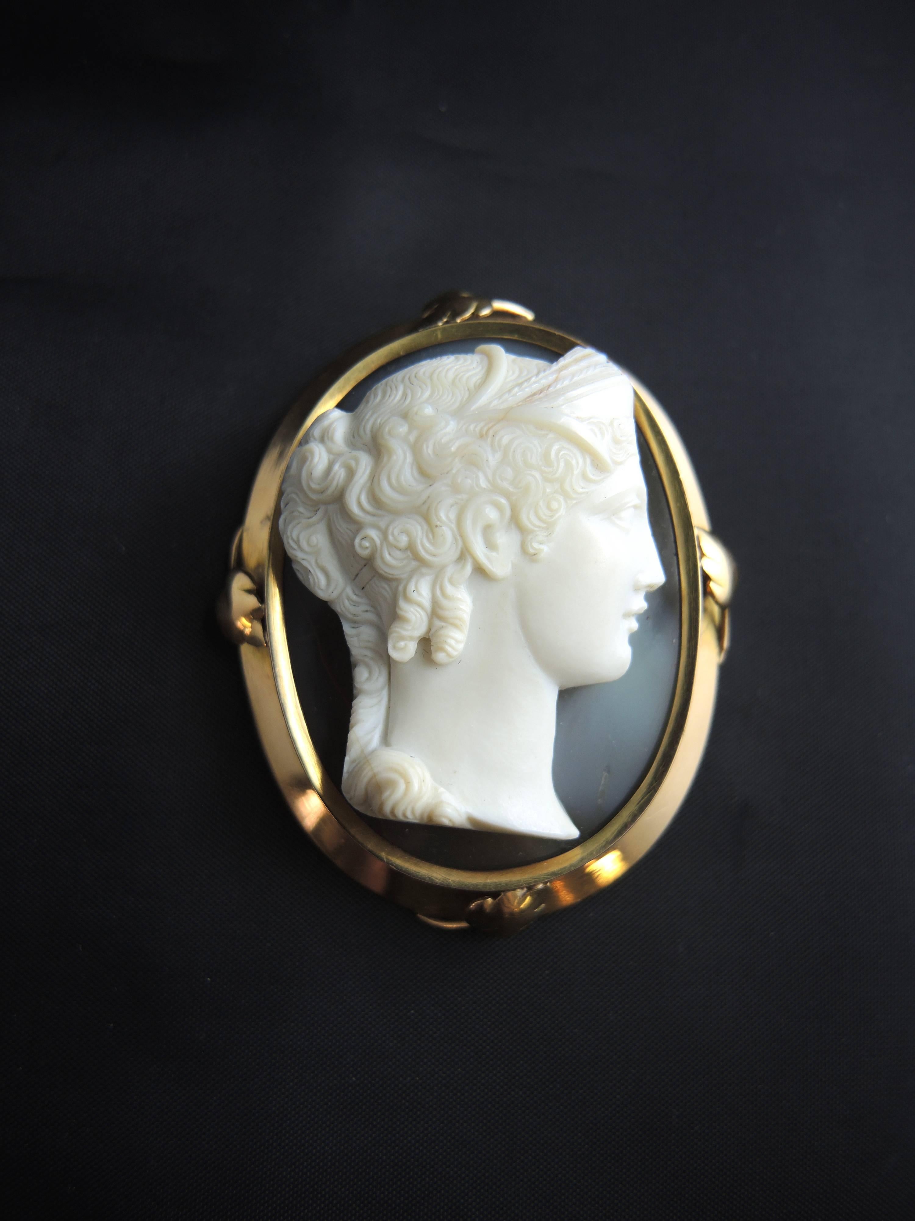 Cameo Brooch and Pendant in 18 carat yellow gold, eagle head hallmark. 

This cameo displays the right profile of a woman with her hair up, engraved into a single piece of agate. The surround is decorated with gold leaves.

It can be worn as a