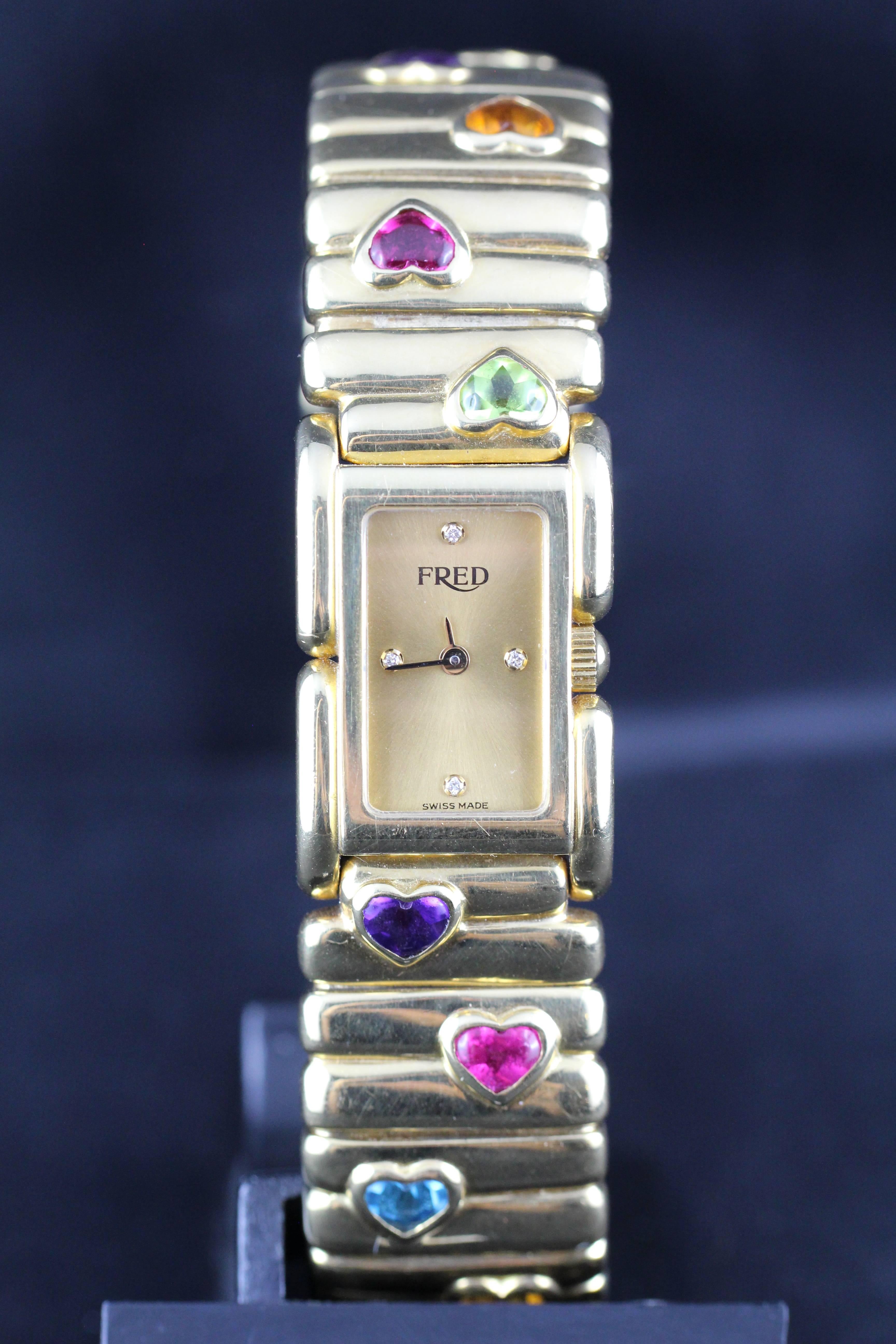 A Fred 18KT yellow gold wrist watch for lady.

Integral 18KT yellow gold fred bracelet set with Amethysts, pink tourmalines, peridots, blue topaz, and citrines.

The gold metal dial features diamonds index.
Sapphire glass.

Quartz battery