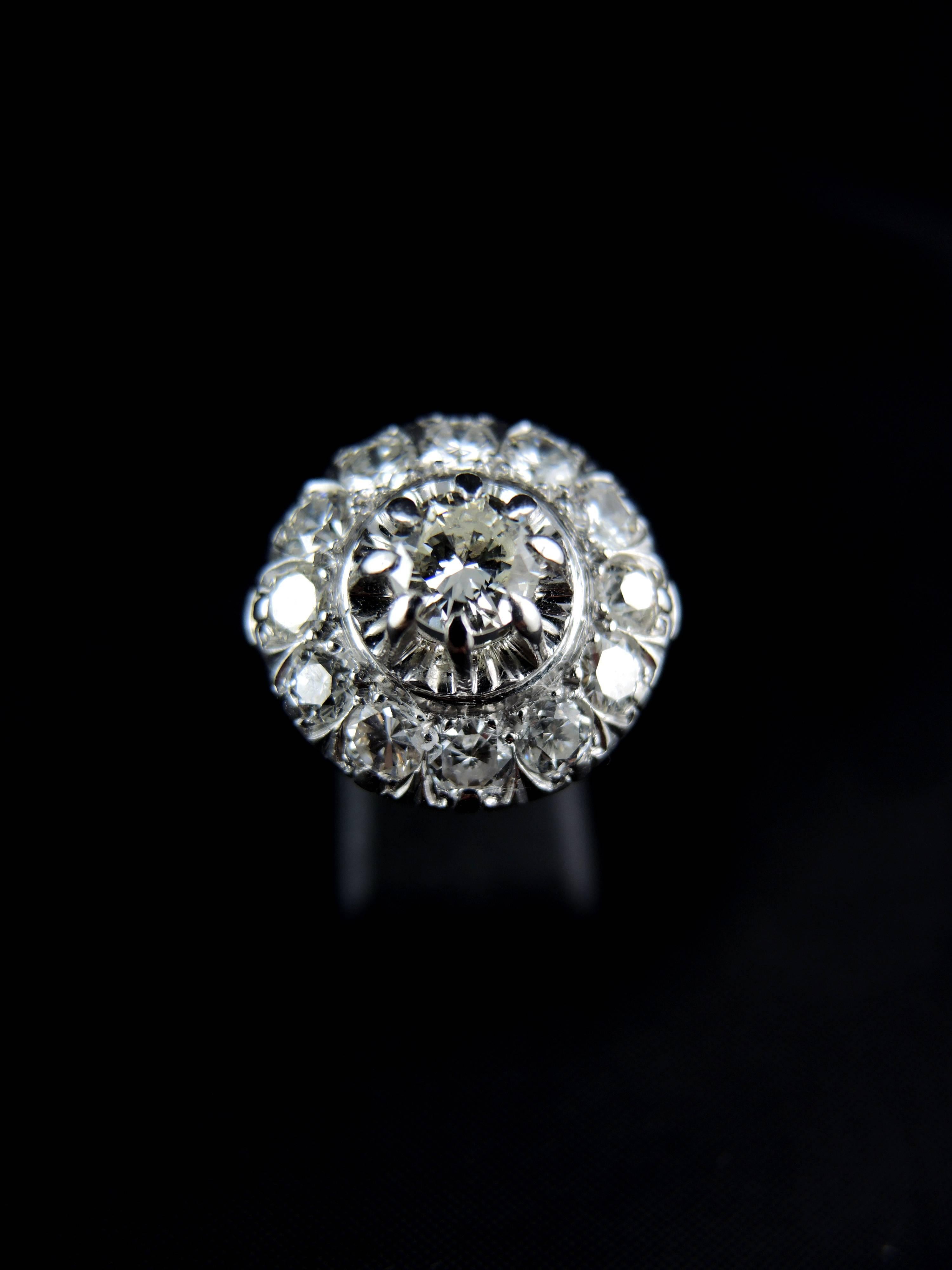 White gold cluster ring (quality mark: head of eagle) set with a central modern brillant cut diamond, weight estimated  around 0,75 Ct (color estimated K, and clarity estimated SI1), surrounded with modern brillant cut diamonds, which total weight
