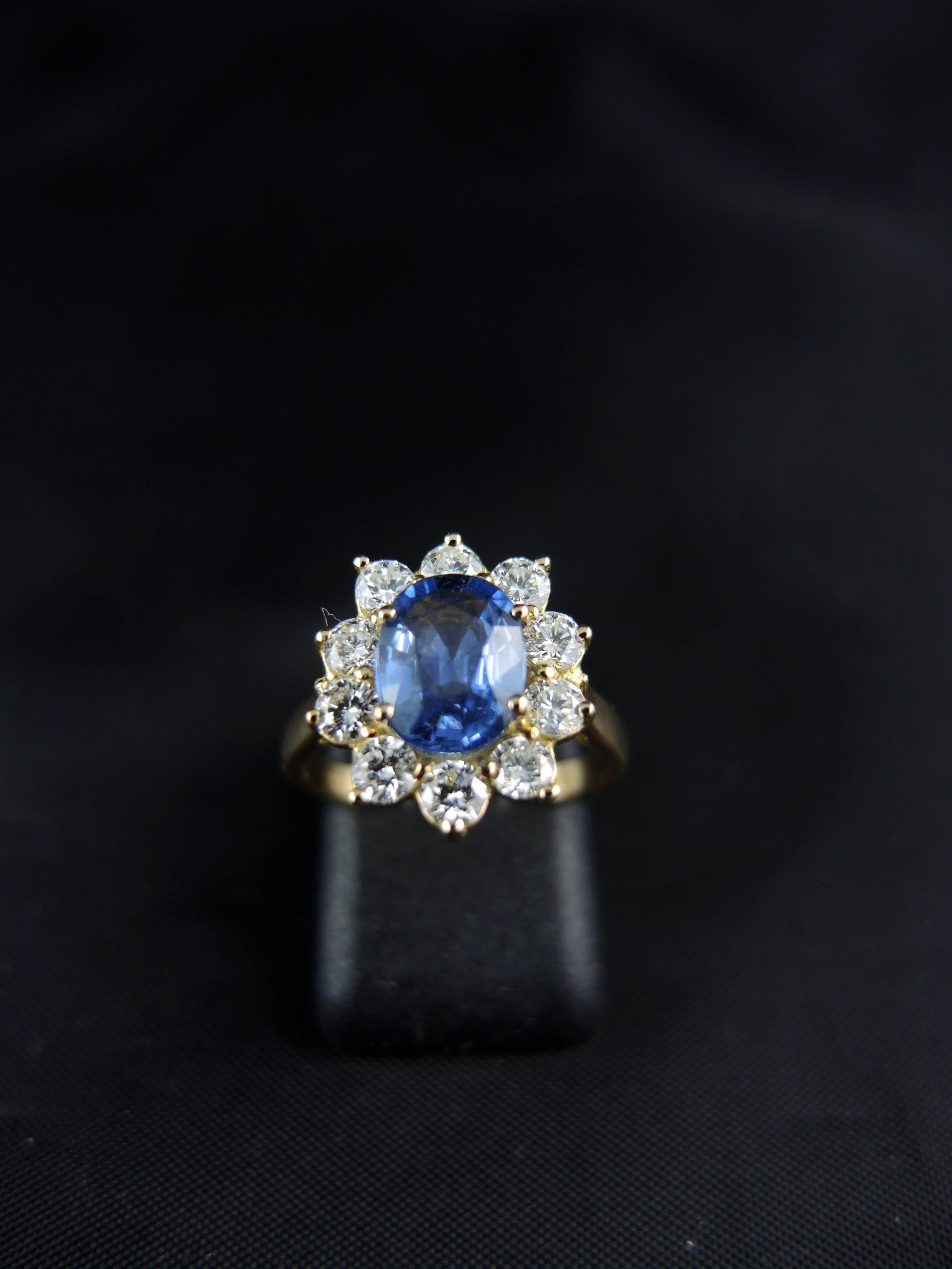 Yellow gold cluster ring (quality mark: head of eagle) set with a central oval sapphire (certainly from Sri Lanka), weight estimated  around 0.80 Ct, surrounded with modern brillant cut diamonds, which total weight is estimated around 0,80